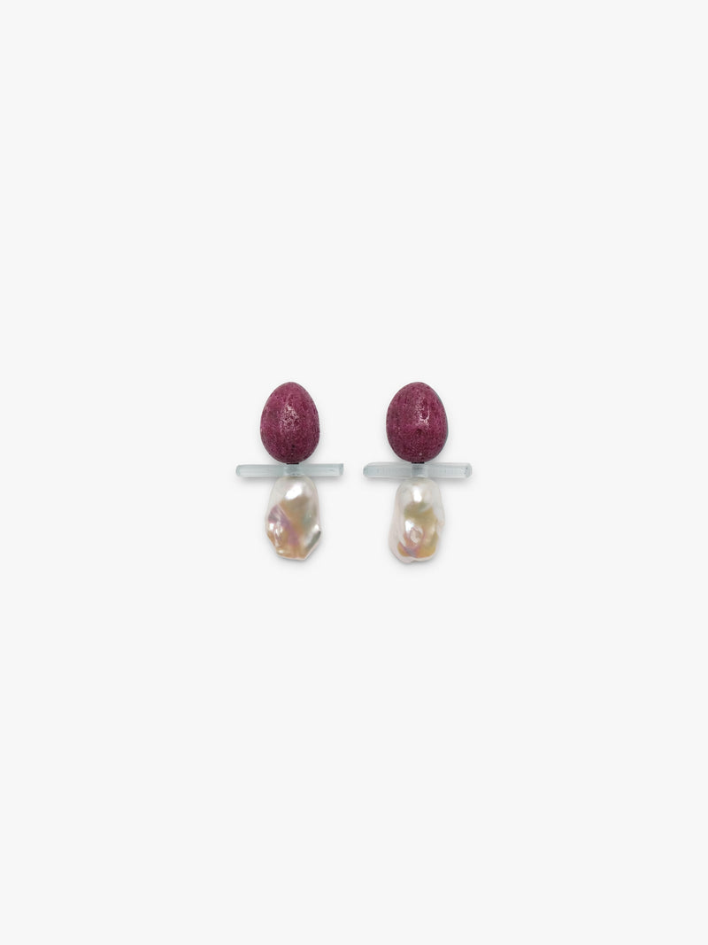 Earrings with a textured purple top with a transparent stone and a baroque pearl underneath. displayed on a white background. 