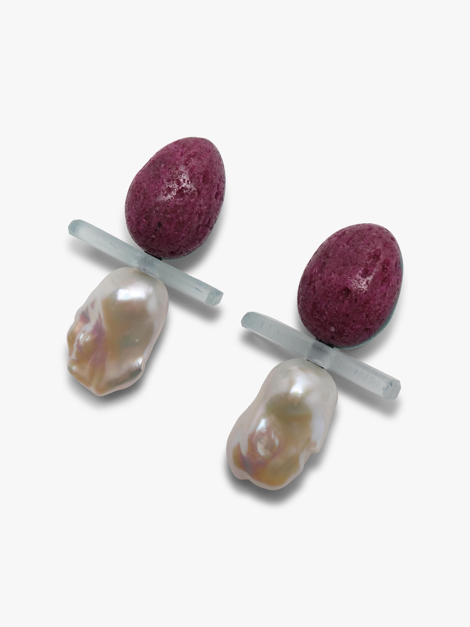 Earrings with a textured purple top with a transparent stone and a baroque pearl underneath. displayed on a white background. 