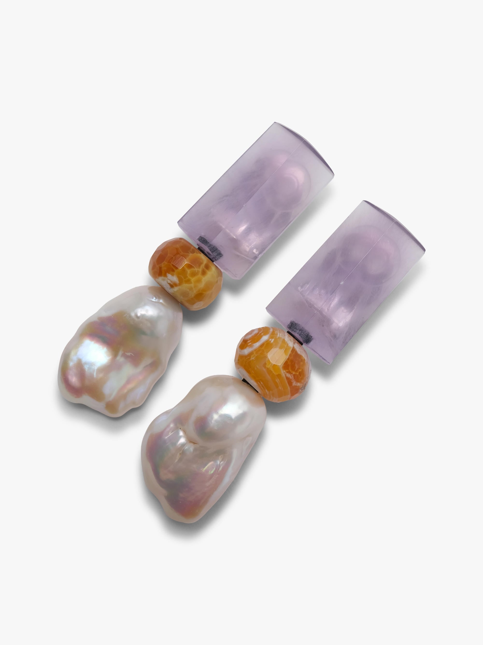 A pair of dangle earrings featuring a lavender rectangular stone, a small amber-brown bead, and a baroque pearl drop, shown on a plain light gray background.