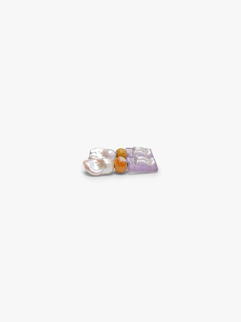 A pair of dangle earrings featuring a lavender rectangular stone, a small amber-brown bead, and a baroque pearl drop, shown on a plain light gray background.