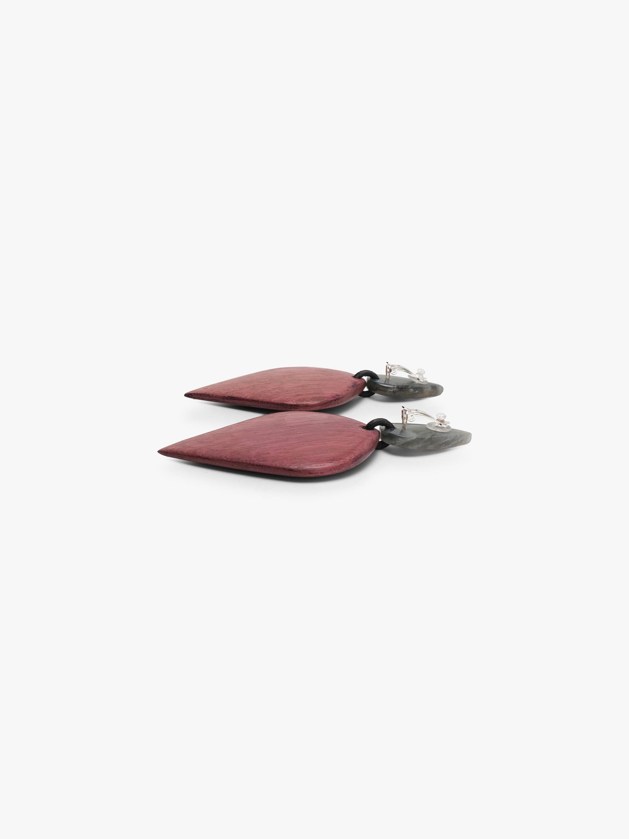 A pair of geometric drop earrings featuring textured, brushed rose-pink teardrop-shaped pendants with small, pointed silver-toned studs on a light gray background.