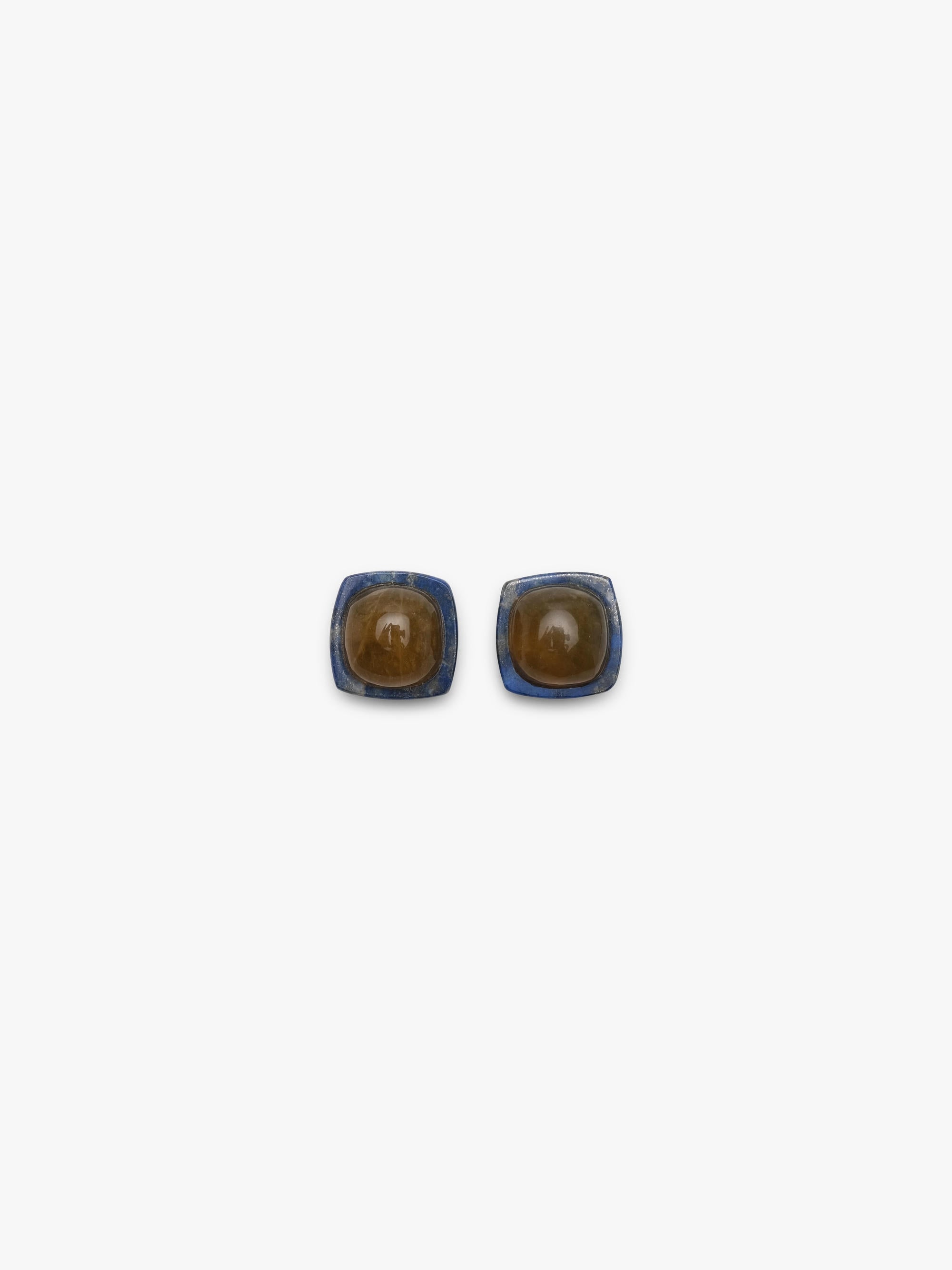 Earrings featuring rounded domeshaped yellow brownish stone set into a deep blue stone. Displayed on a white background. 