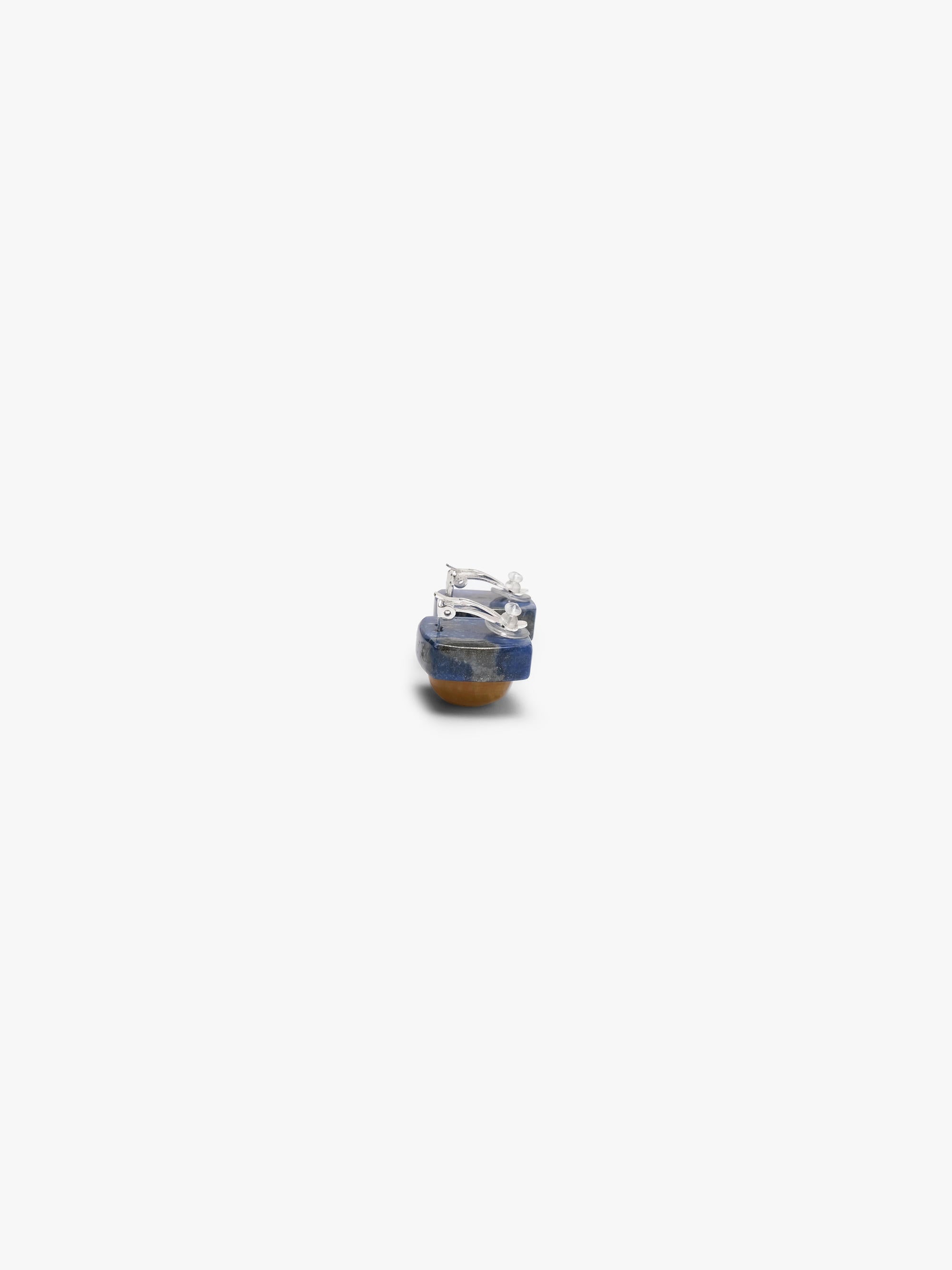 Earrings featuring rounded domeshaped yellow brownish stone set into a deep blue stone. Displayed on a white background. 