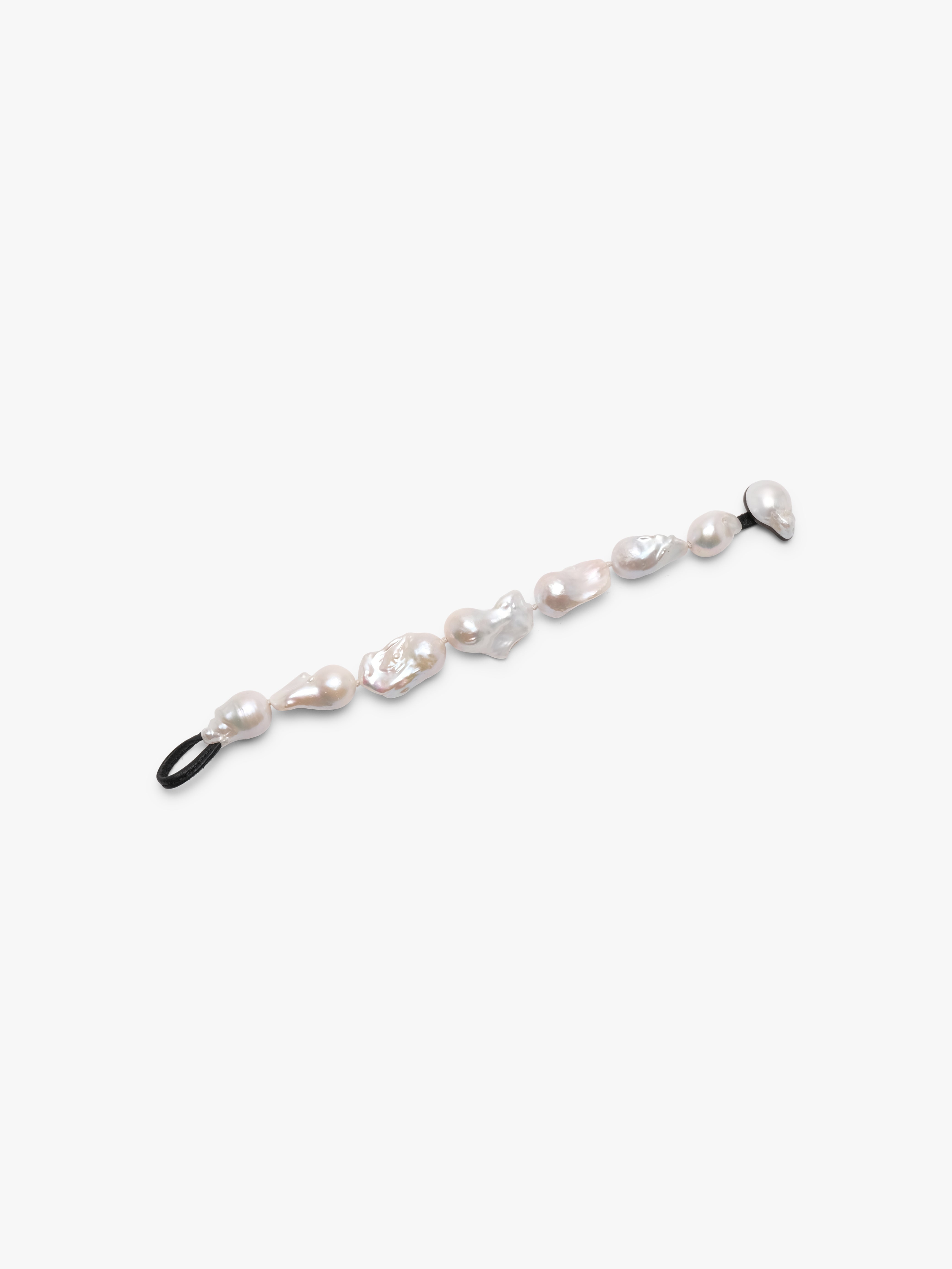 A bracelet made of baroque pearls with a leather strap, featuring a toggle clasp lock.