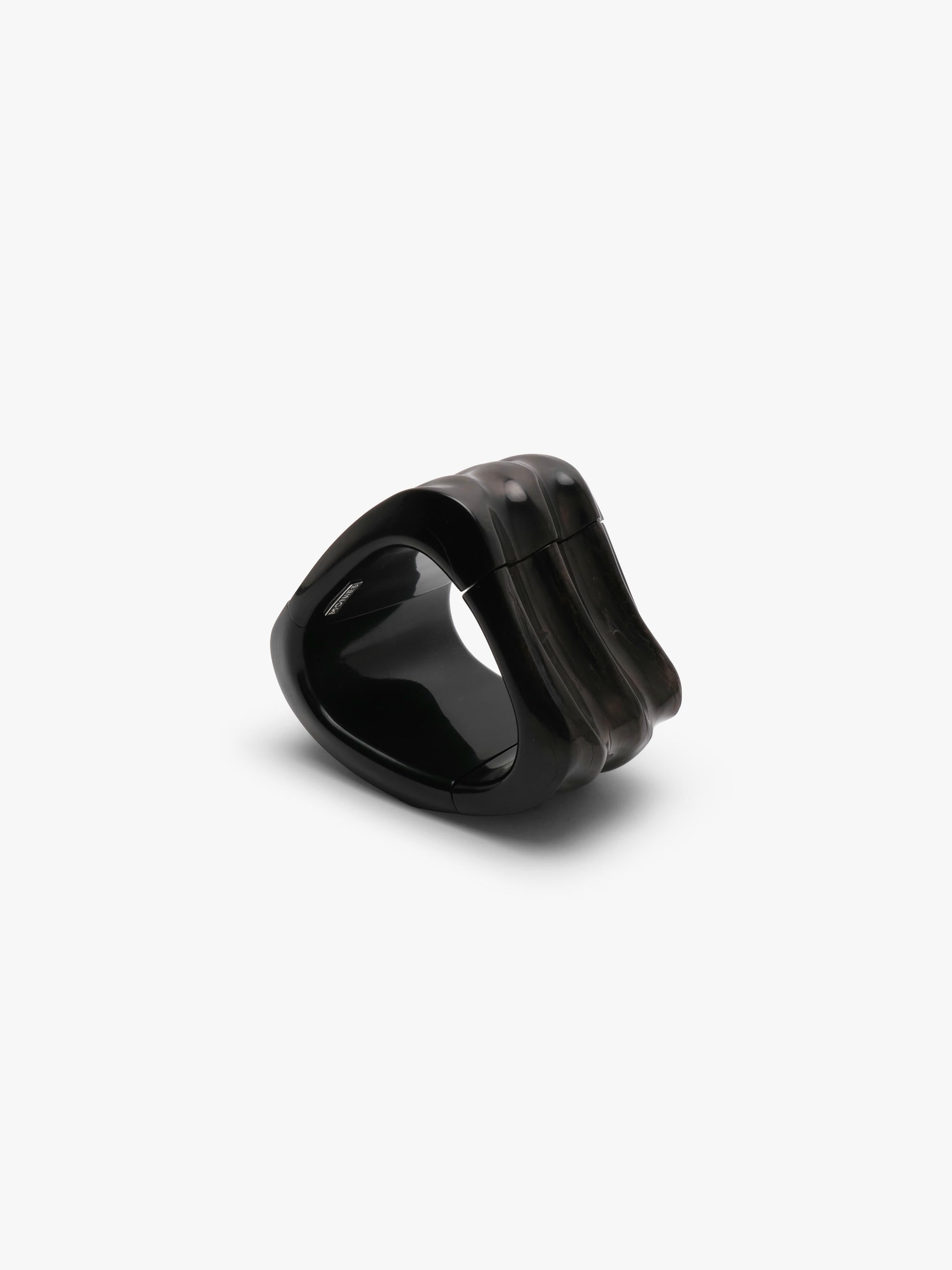 Black bracelet made of buffalo horn, with natural ridges, displayed on a white background
