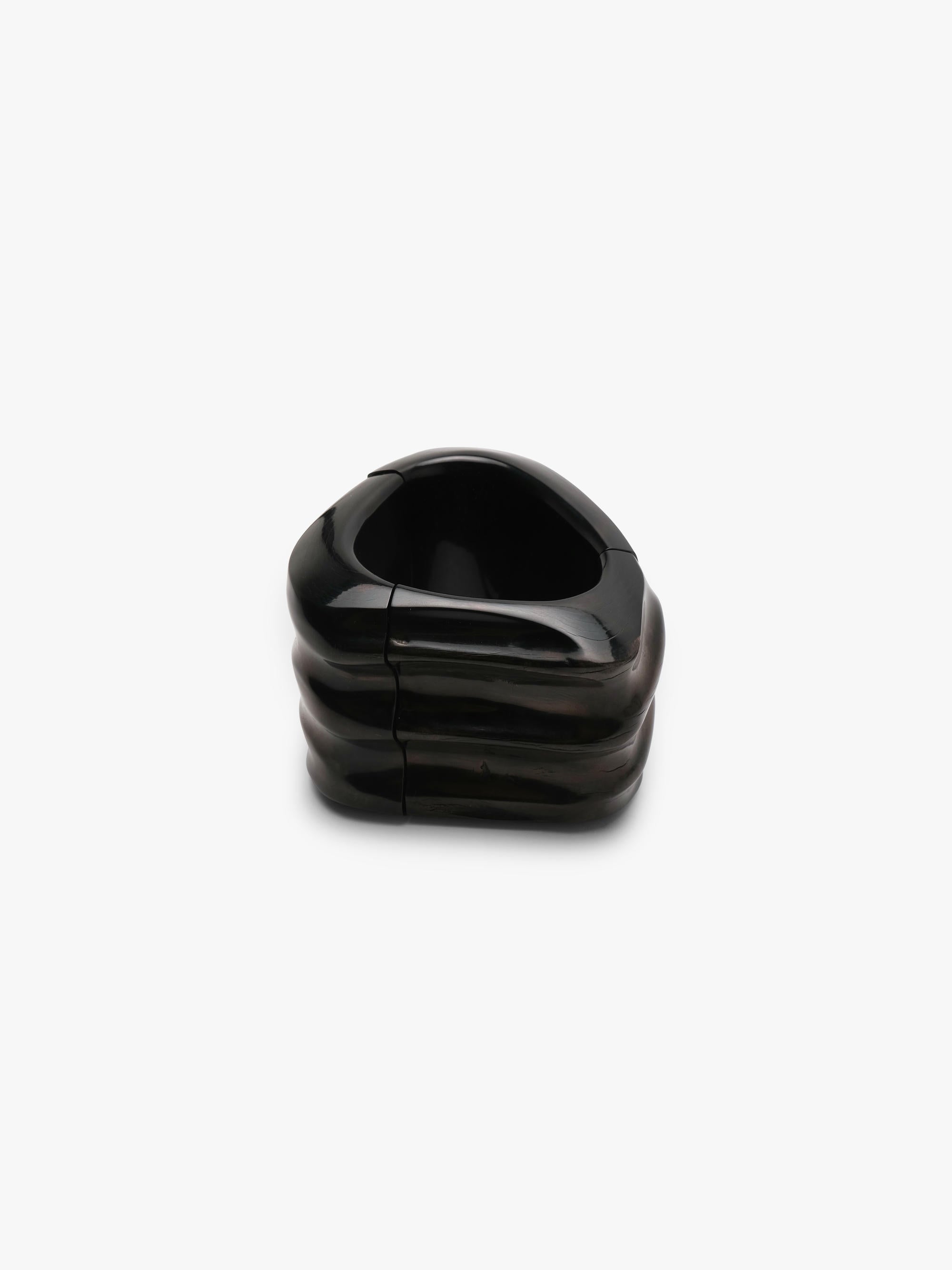 Black bracelet made of buffalo horn, with natural ridges, displayed on a white background