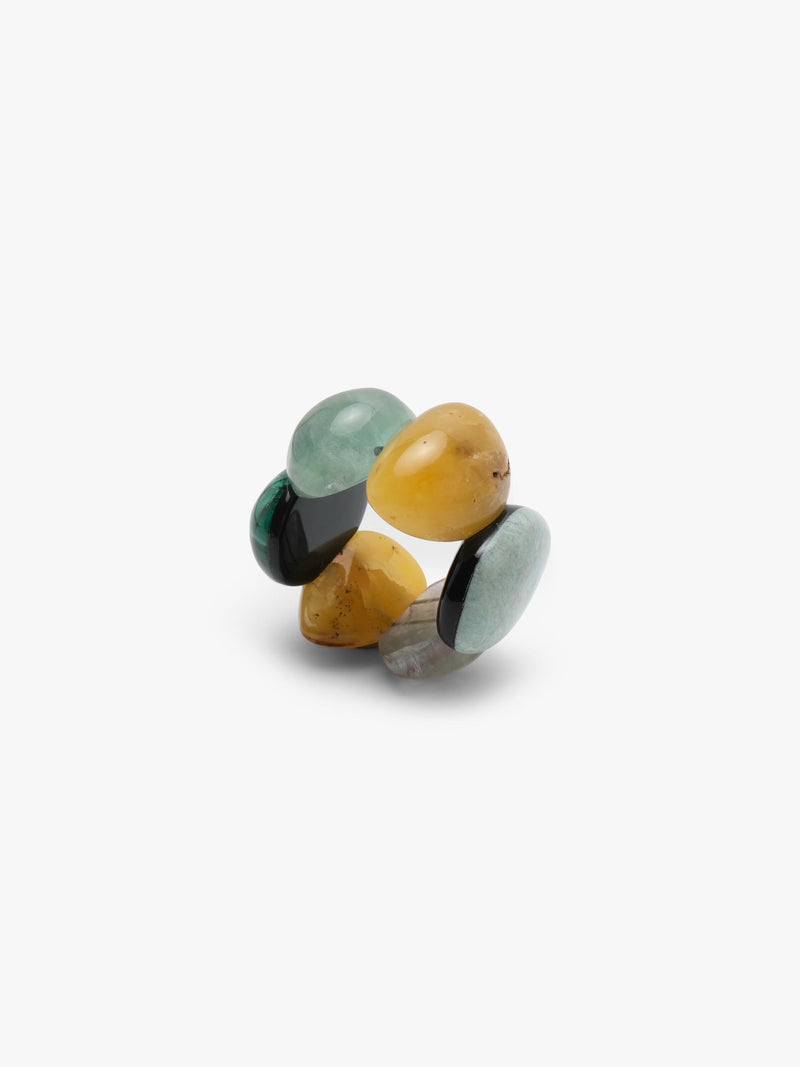 A bracelet of five polished teardrop-shaped gemstone pendants in various colors including yellow, green, gray, and black, arranged on a plain light gray background.