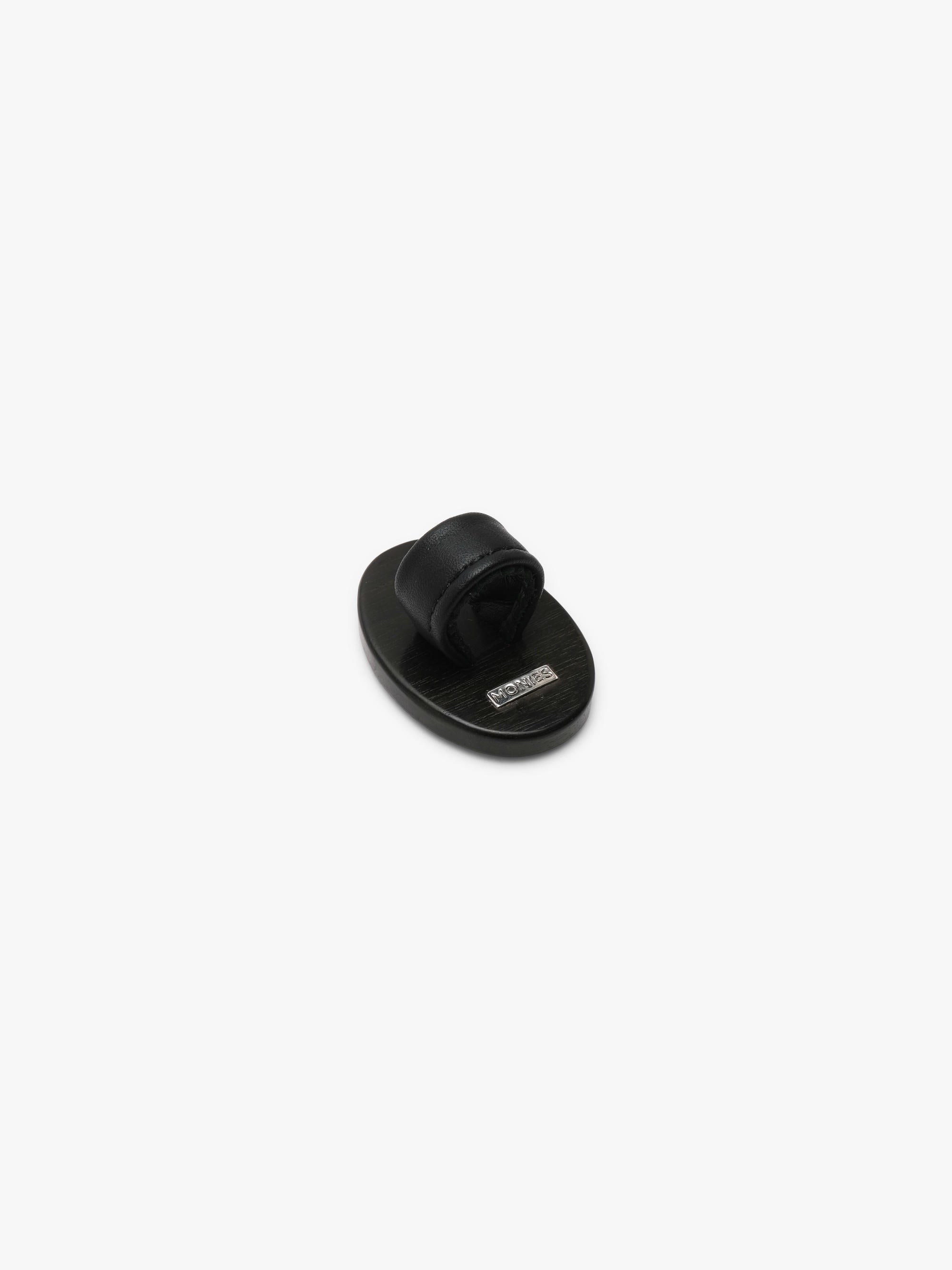 A ring with a patterened black and brown stone , shown against a solid off-white background.