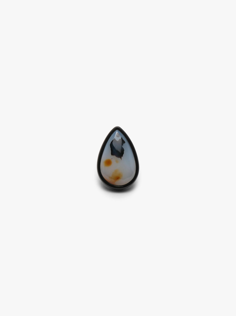 A ring with a white and orange pear-shaped gemstone set into dark wood on a white background