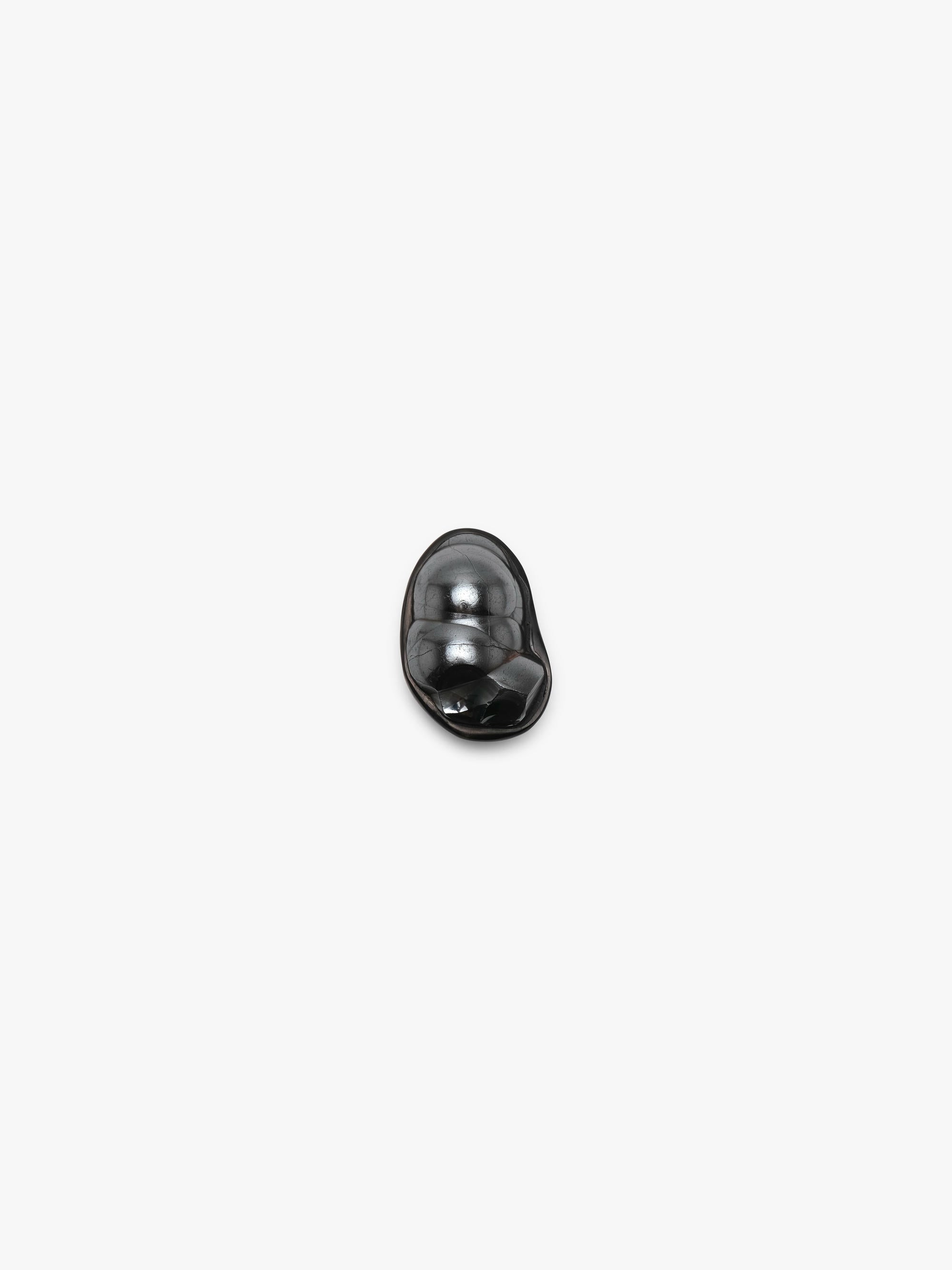 A black sculptural metallic textured ring with a black stone set into black horn with a leather band, displayed on a white background.