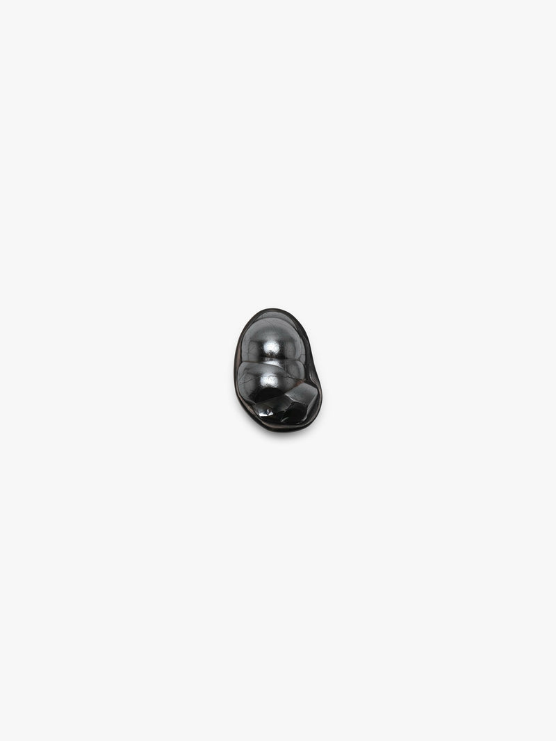 A black sculptural metallic textured ring with a black stone set into black horn with a leather band, displayed on a white background.
