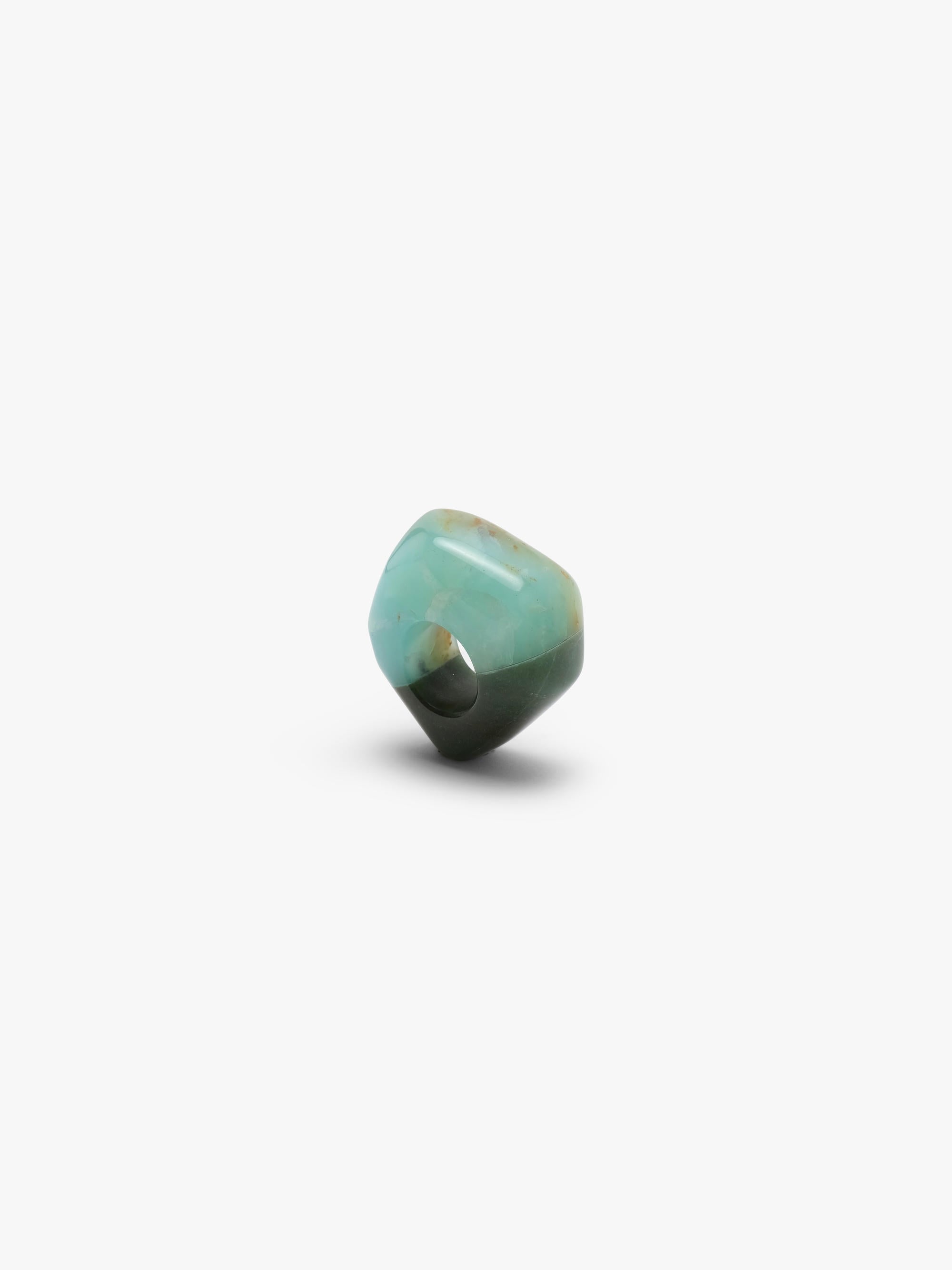 A , polished turquoise- and dark green colored stone ring with natural brown matrix inclusions, centered on a plain white background.