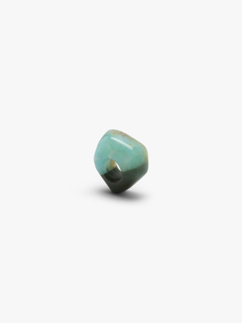 A , polished turquoise- and dark green colored stone ring with natural brown matrix inclusions, centered on a plain white background.
