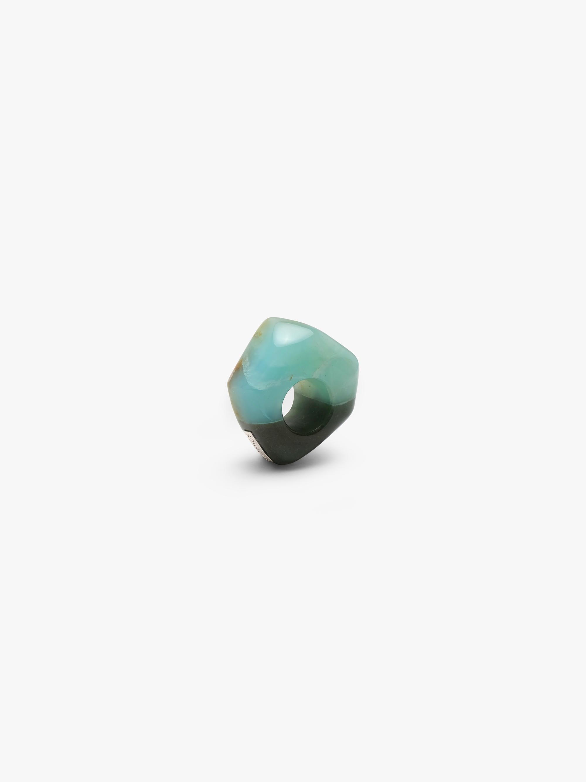 A , polished turquoise- and dark green colored stone ring with natural brown matrix inclusions, centered on a plain white background.