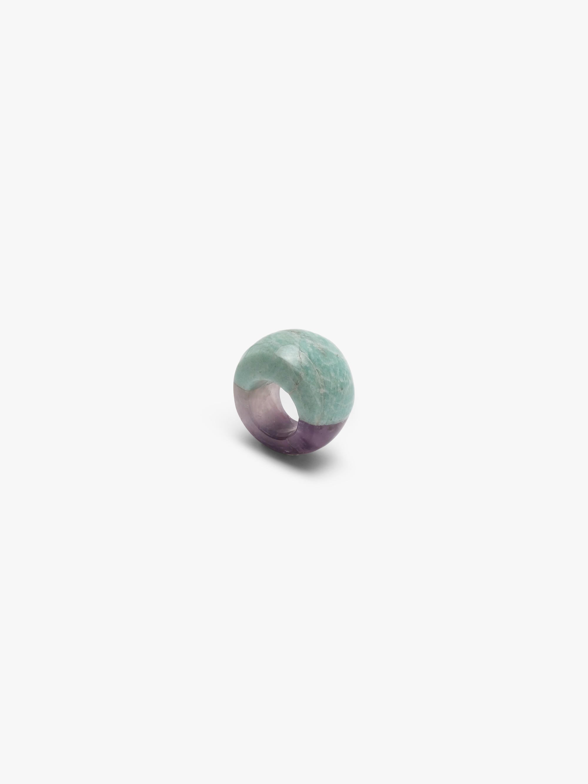 A curved ring mixing a light blue marble-looking stone wth a light purple stone, displayed on a white background.