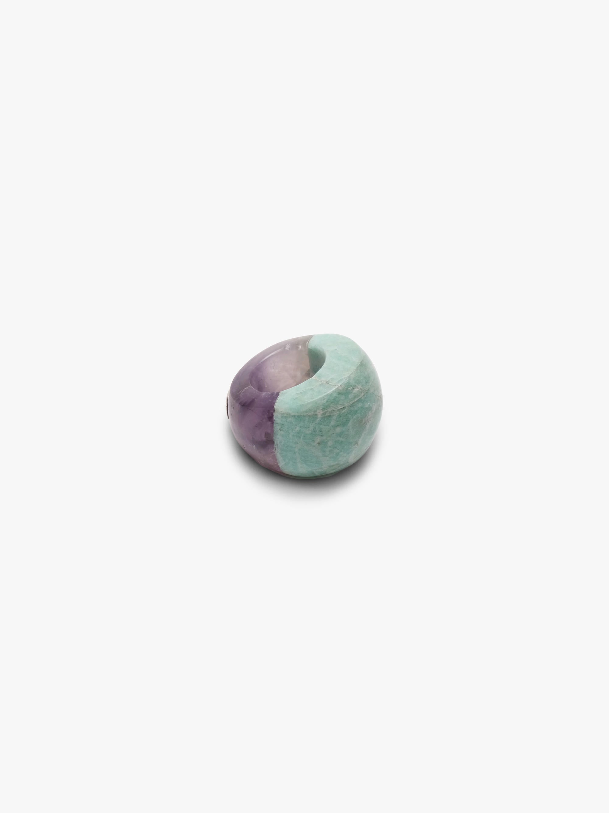 A curved ring mixing a light blue marble-looking stone wth a light purple stone, displayed on a white background.