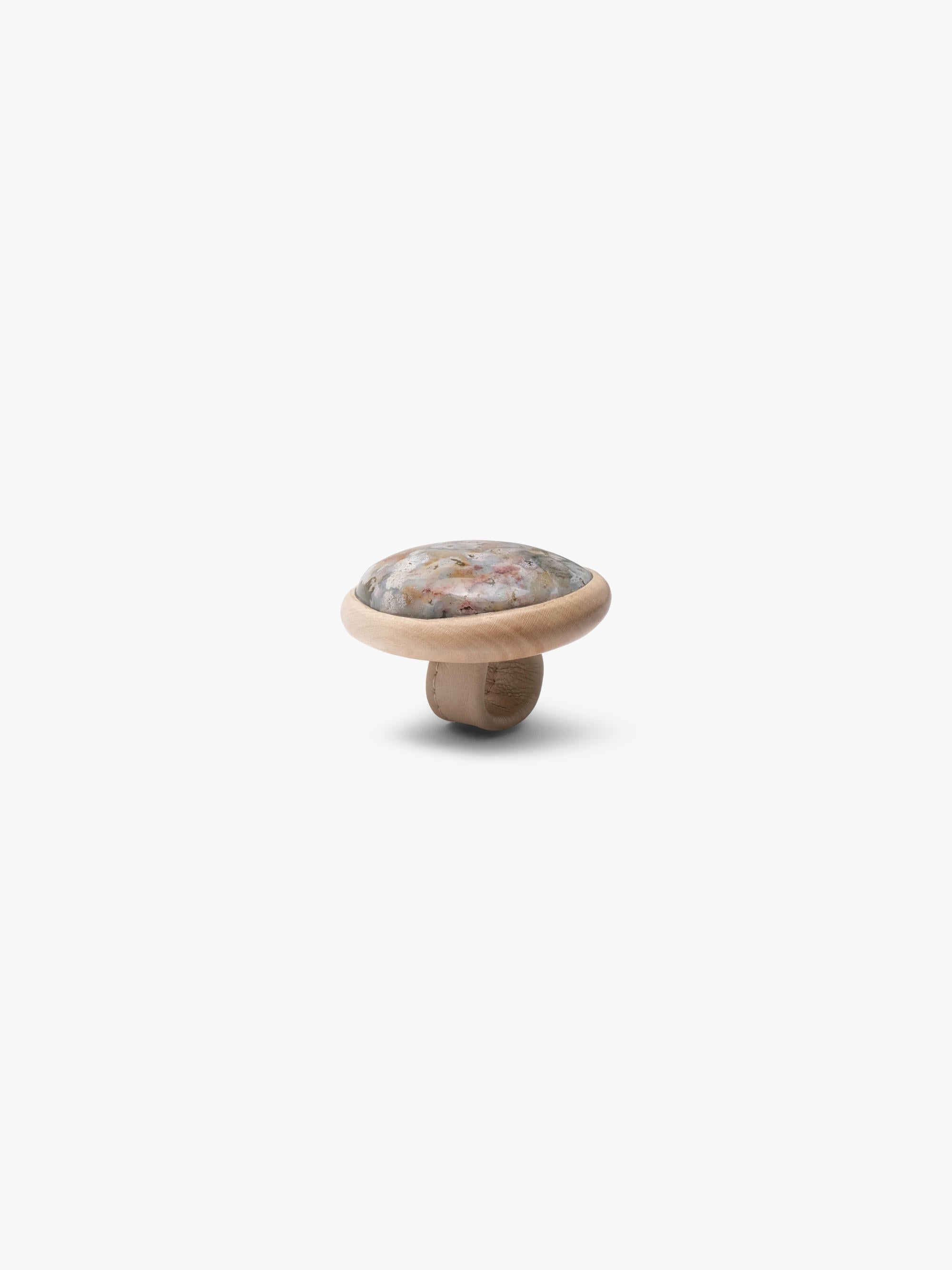 A large ring, with a marble stone top set into a light wood, with a light colored leather band. Displayed on a white background
