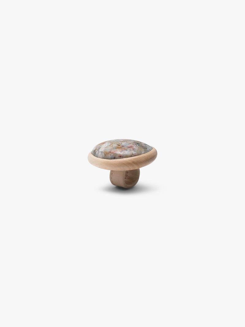 A large ring, with a marble stone top set into a light wood, with a light colored leather band. Displayed on a white background