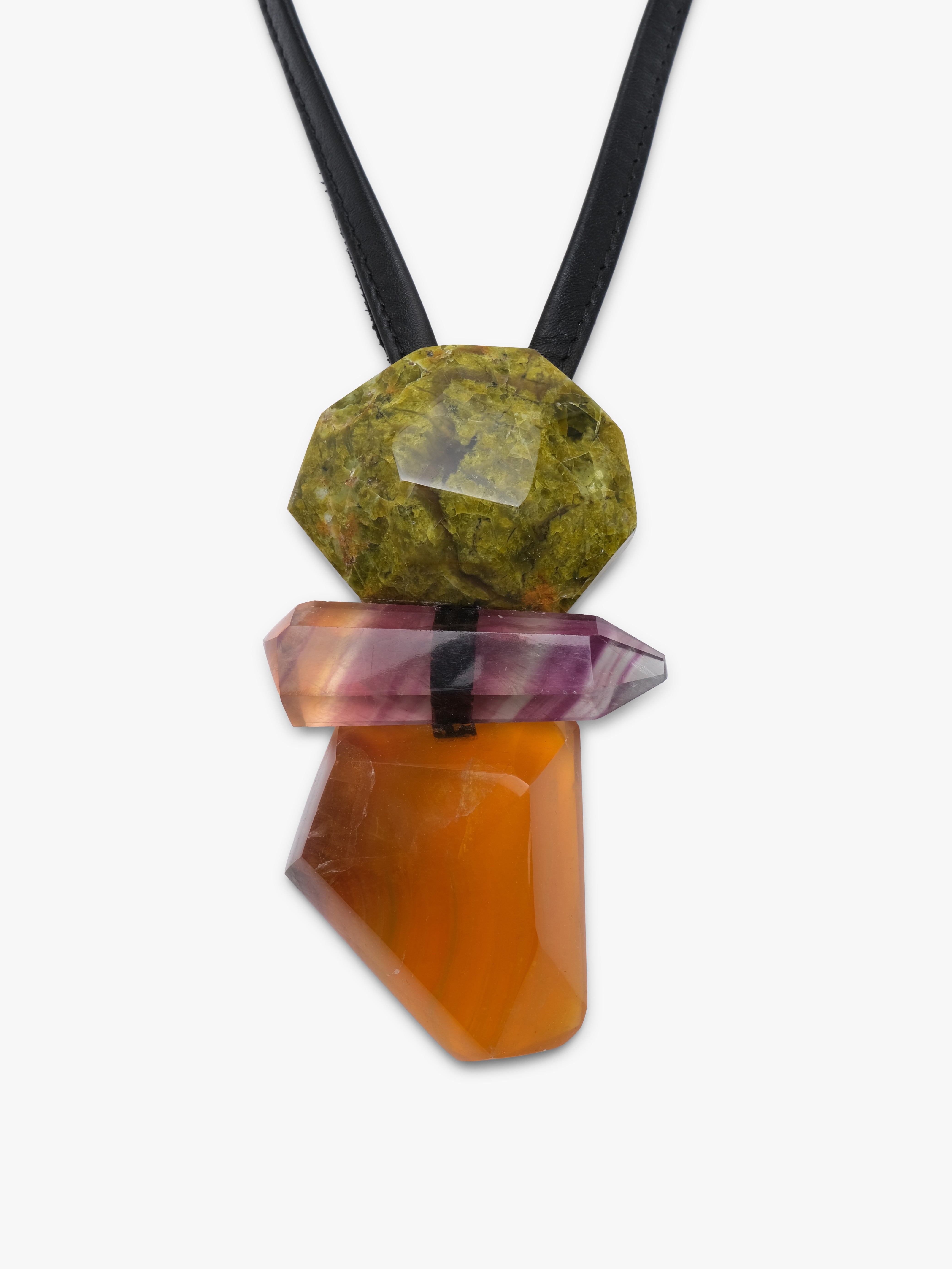 A black cord necklace featuring a stacked crystal pendant with a green stone on top, a pinkish-purple stone in the middle, and a faceted orange stone at the bottom, shown against a plain light gray background.