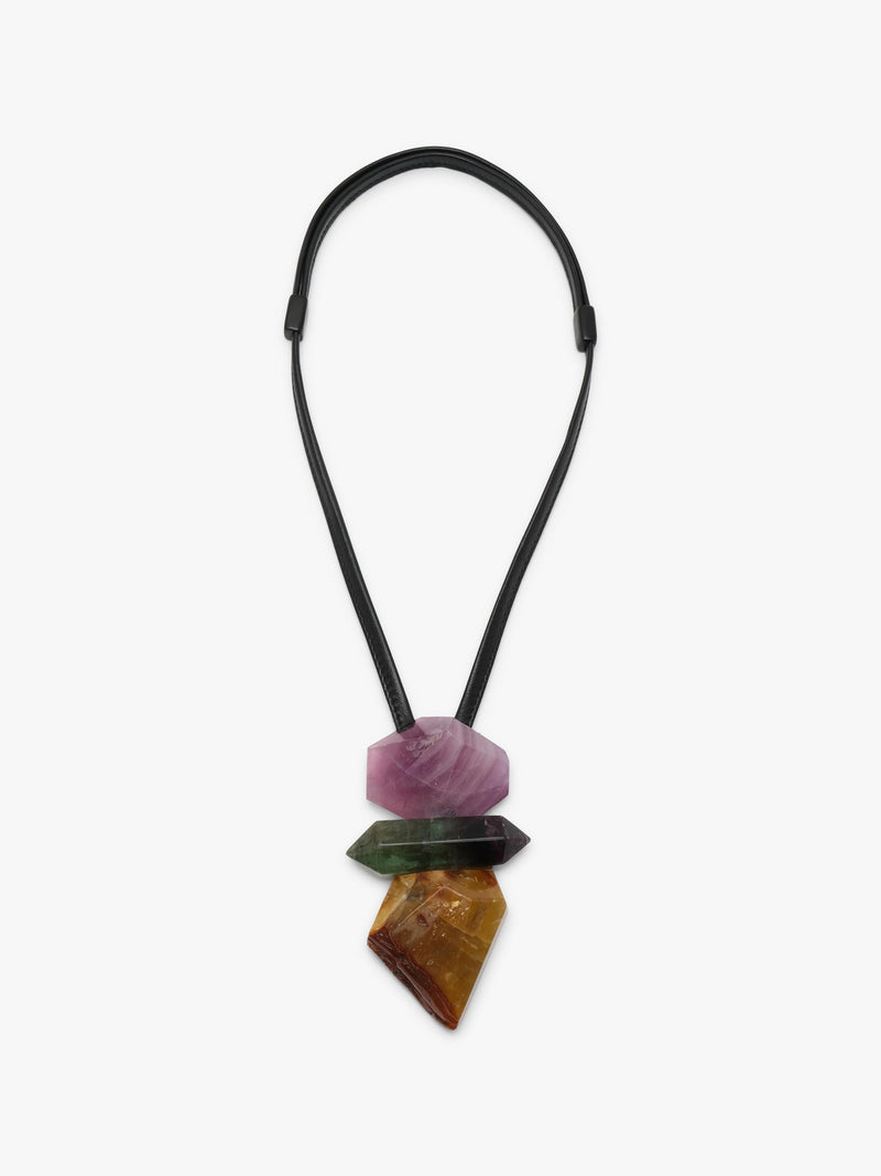 A multi-stone necklace pendant featuring a black elastic cord and three stacked, tapered crystal points in pink, green, and brown, displayed against a light gray background.