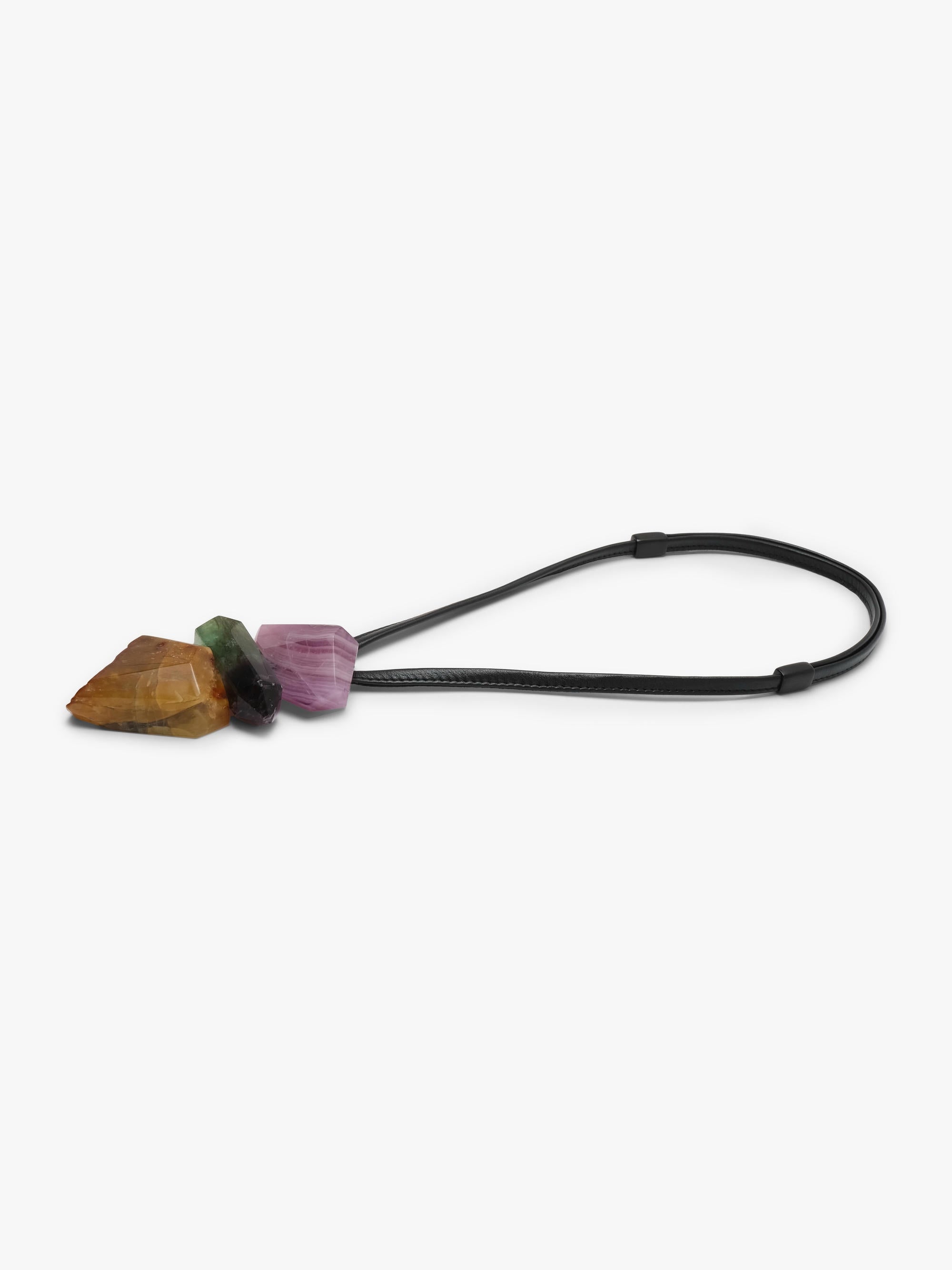 A black elastic cord keychain or bag charm featuring three small polished crystal stones in brown, green, and purple, set against a plain light gray background.