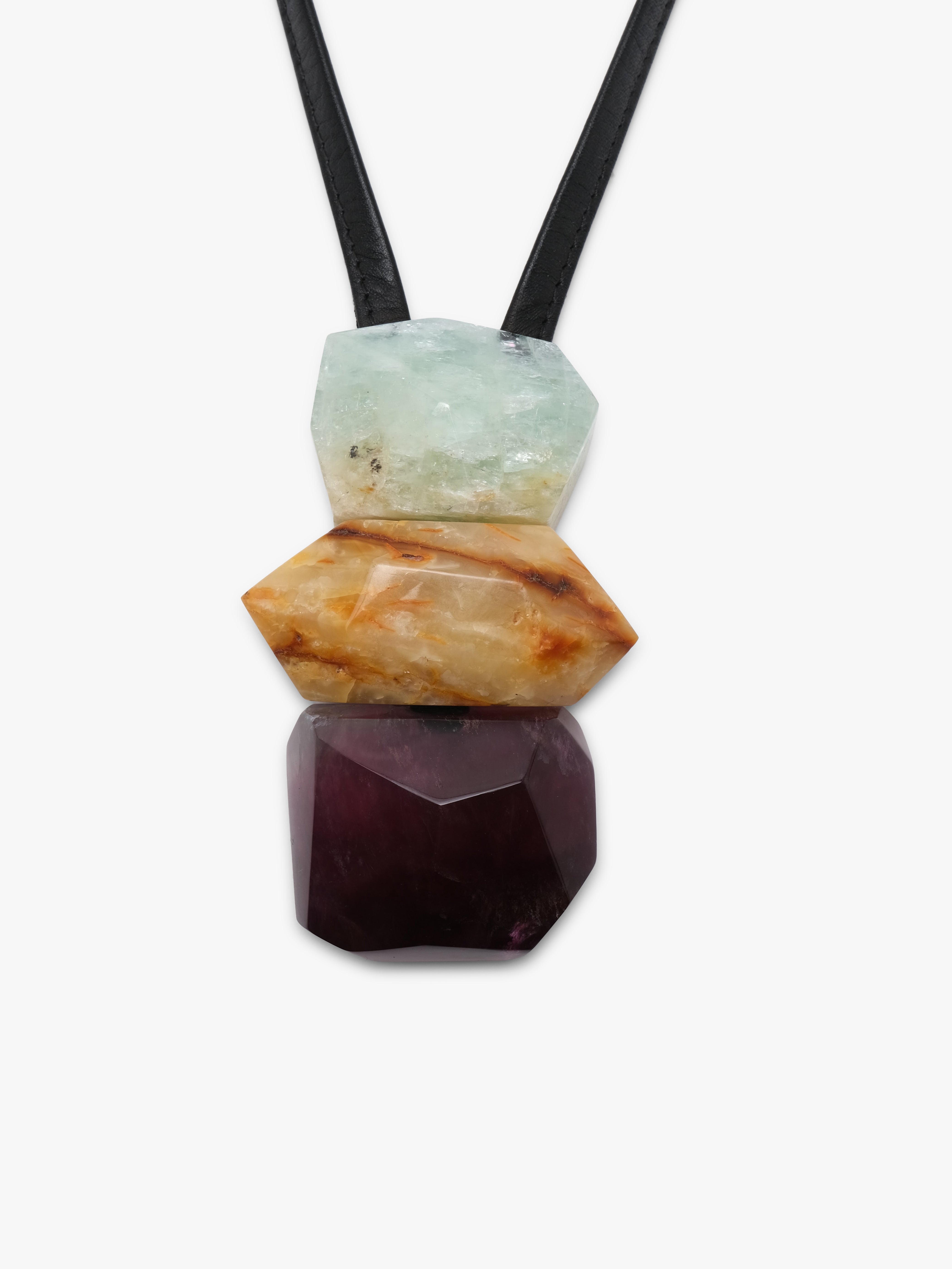 Black leather pendant with a cluster of natural stones in light blue, golden and purple colors. Displayed on a white background.