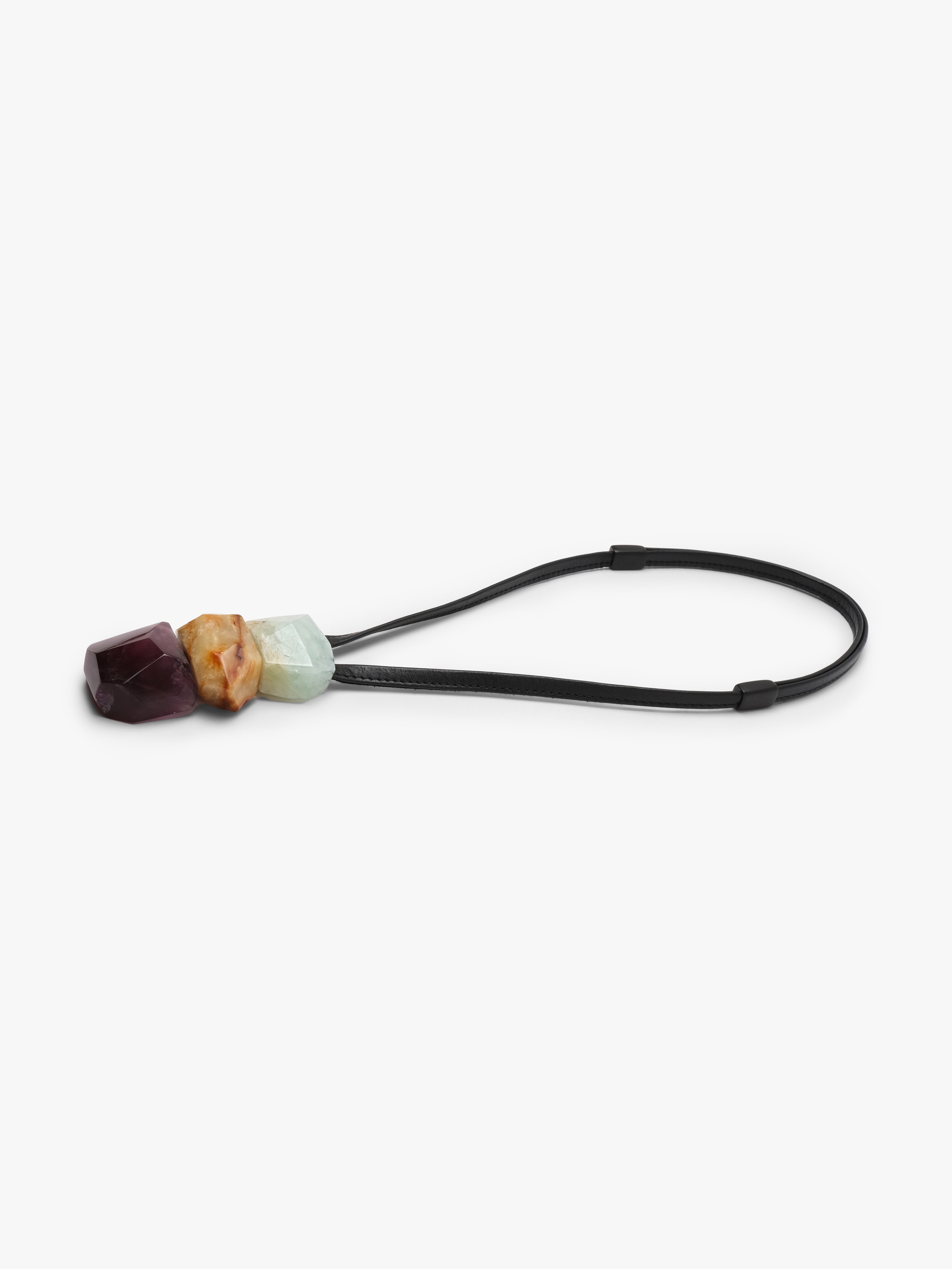 Black leather pendant with a cluster of natural stones in light blue, golden and purple colors. Displayed on a white background.