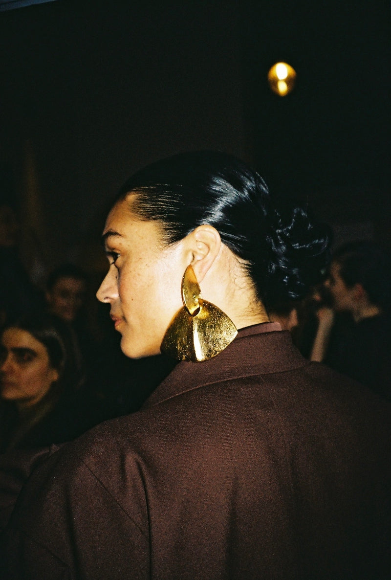 A pair of gold-colored clip-on earrings with a geometric design, featuring acacia wood and goldfoil.