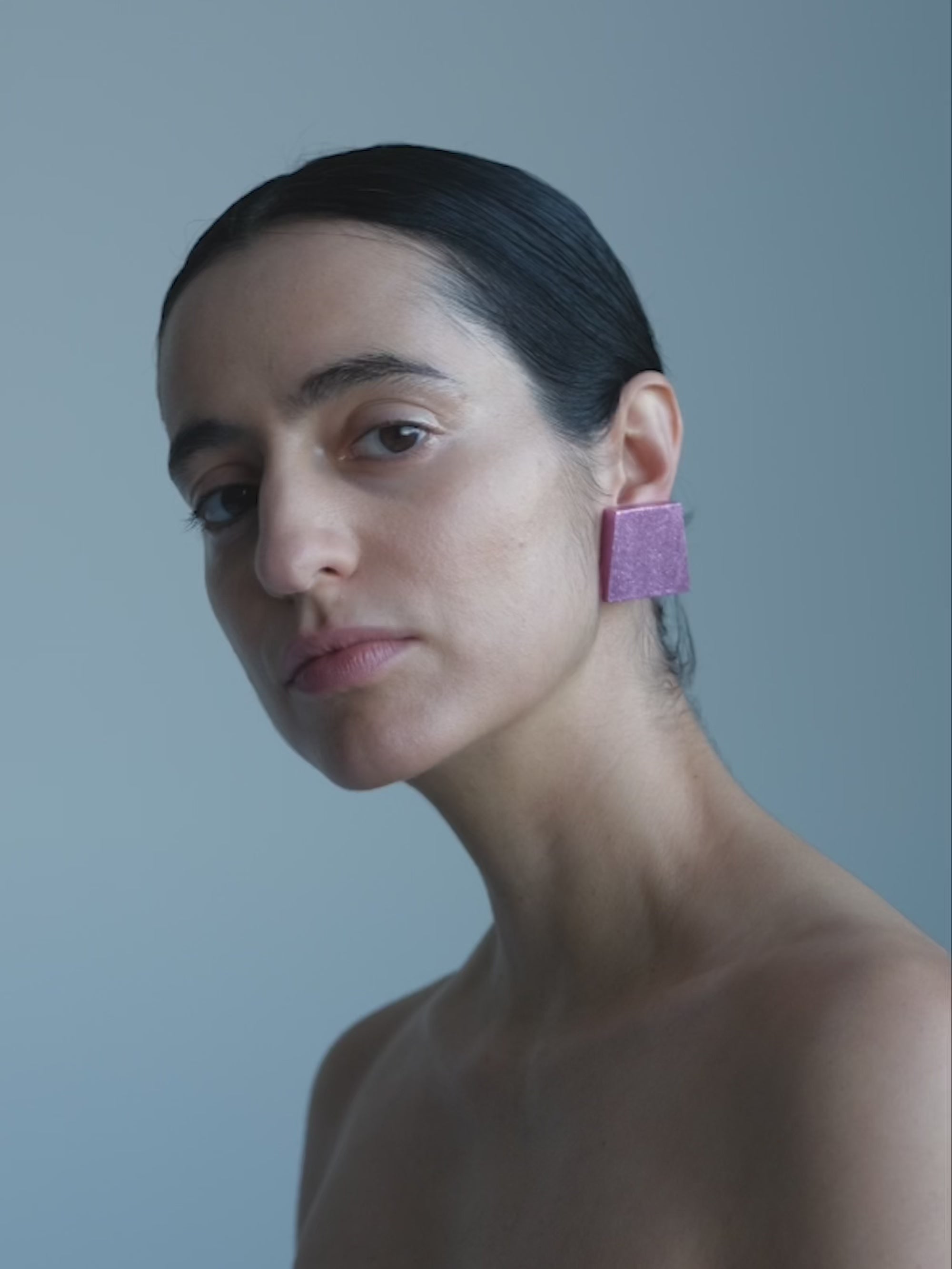 woman wearing pink square earrings on a white background