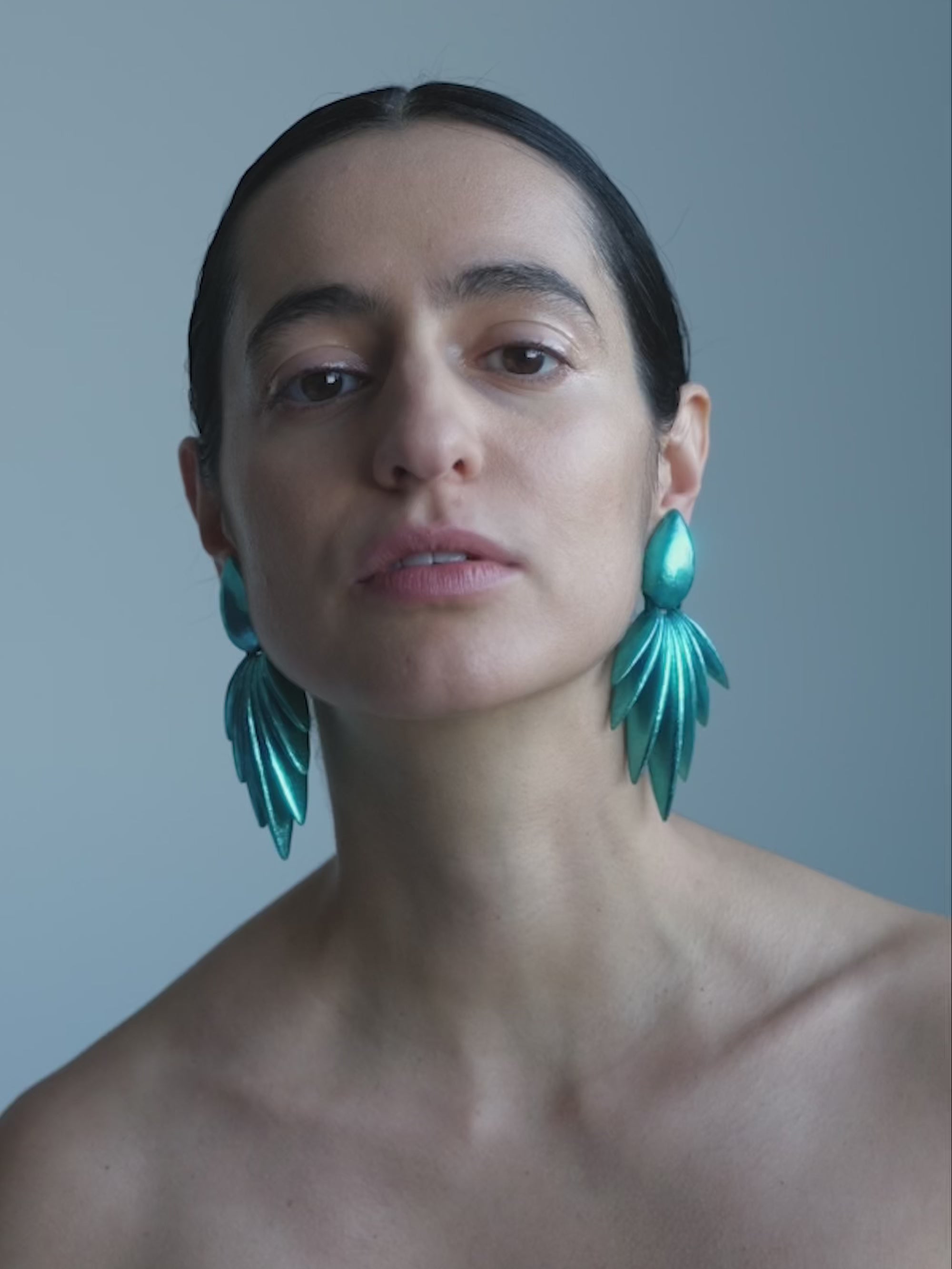 Woman wearing a Pair of teal octopus-shaped earrings on a white background