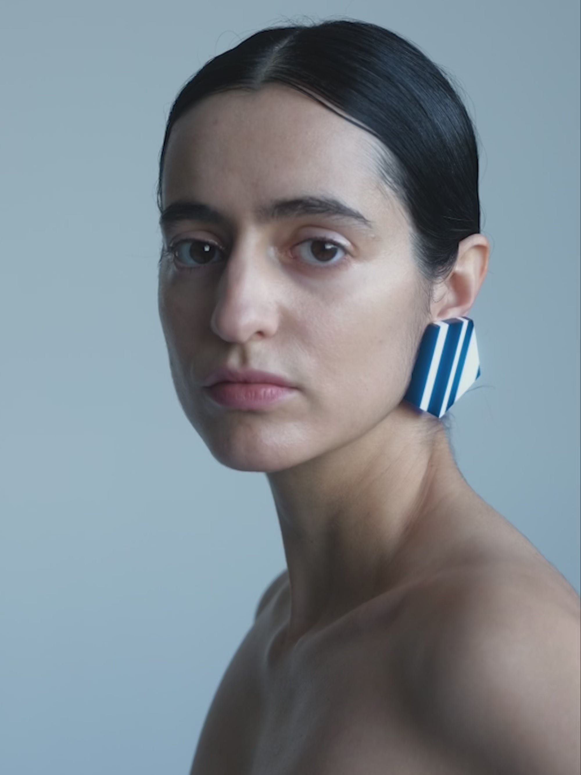 Woman wearing Pair of geometrical black and white earrings on a plain background