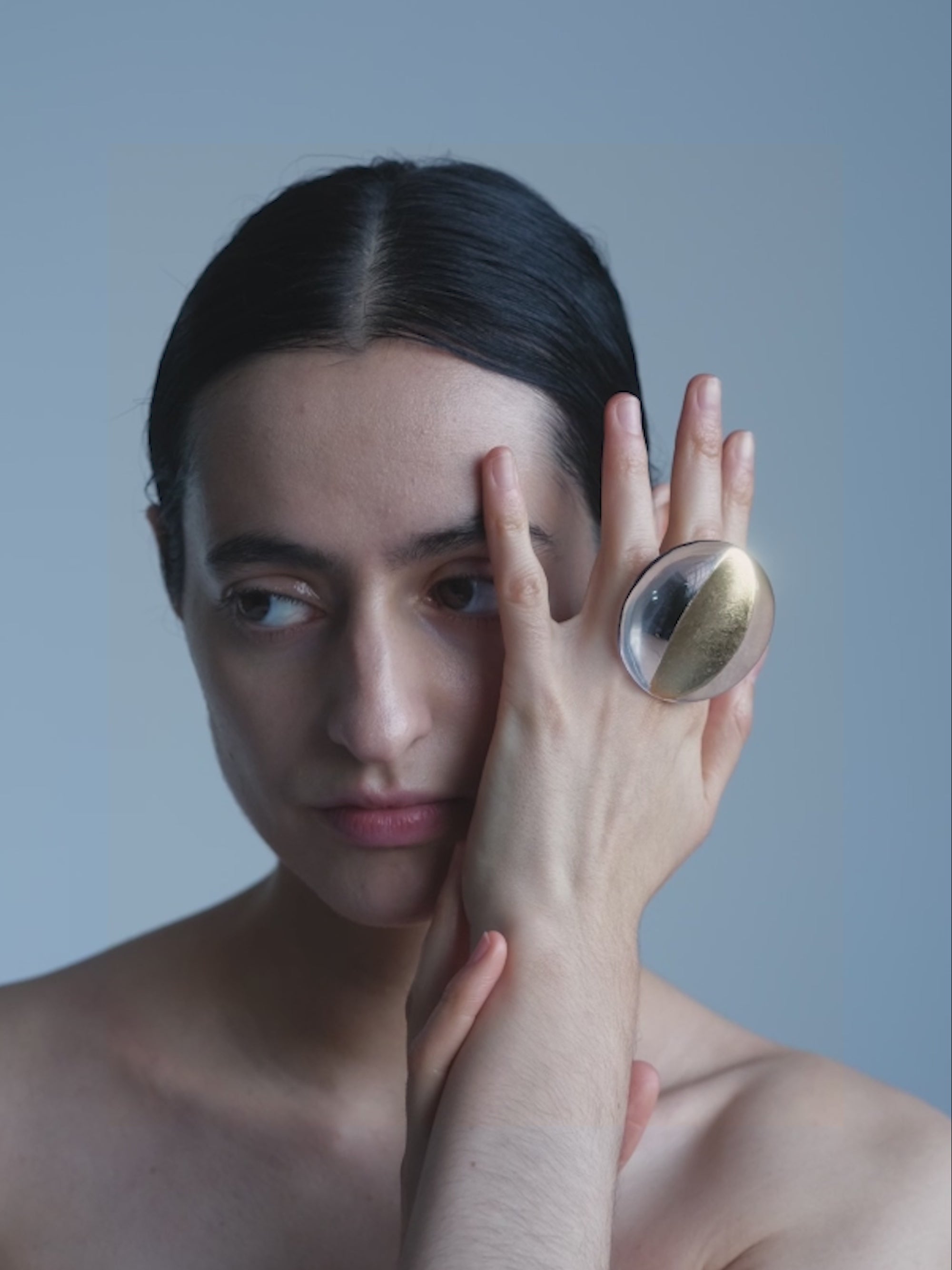 Woman with a large ring on her finger against a plain background