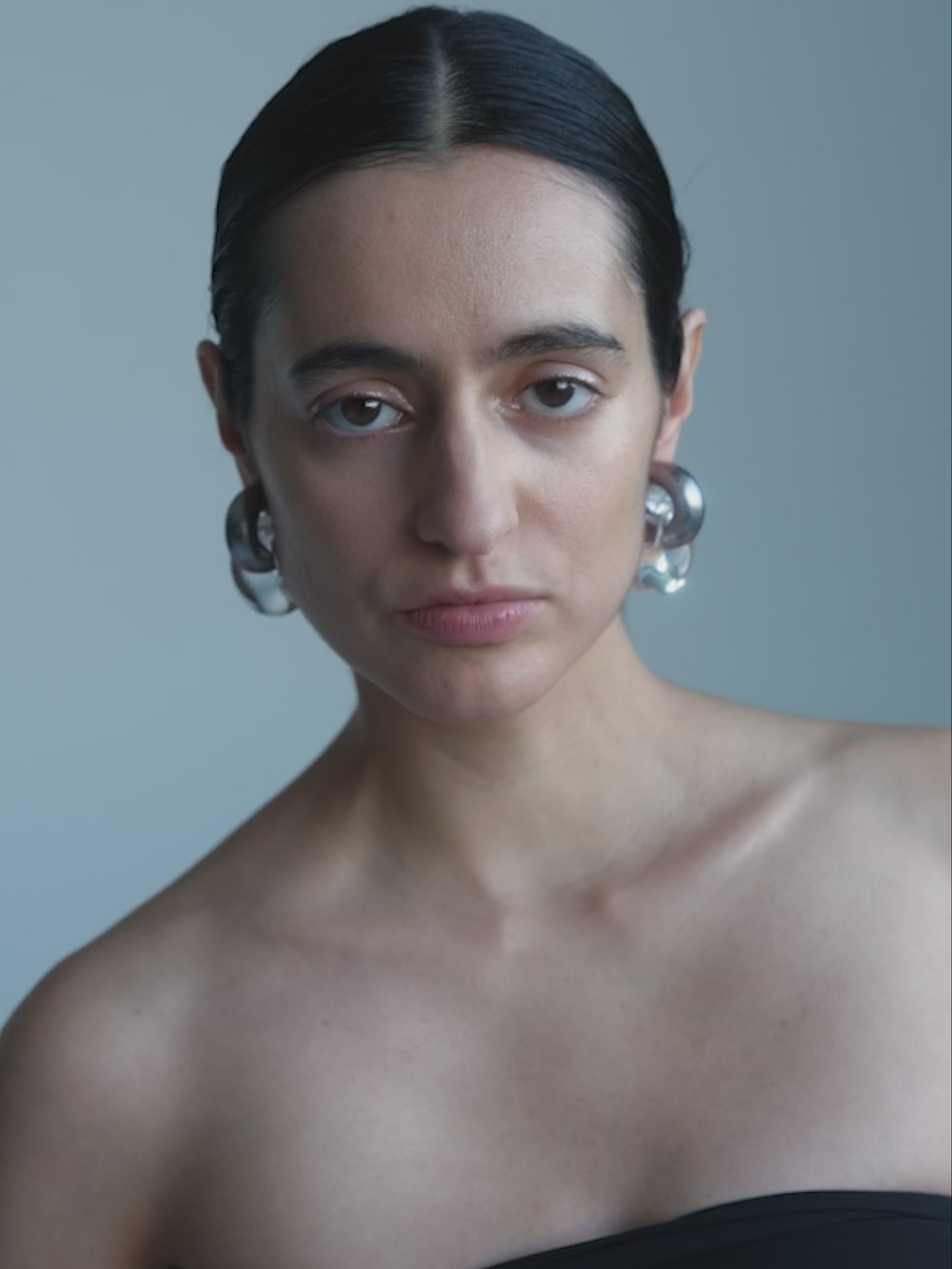 Woman wearing Pair of silver hoop earrings on a white background