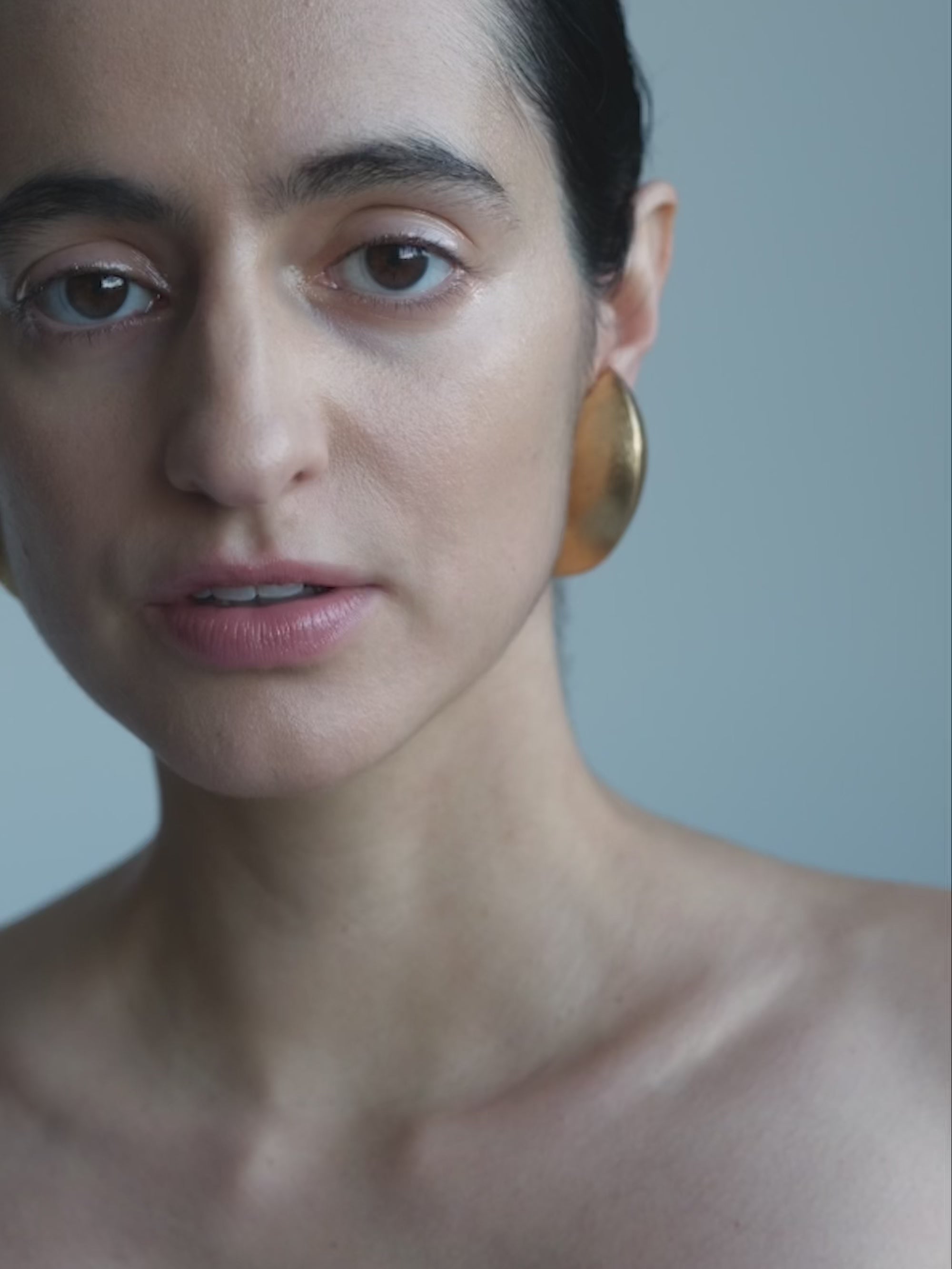 Woman wearing Gold leafshaped earrings on a white background