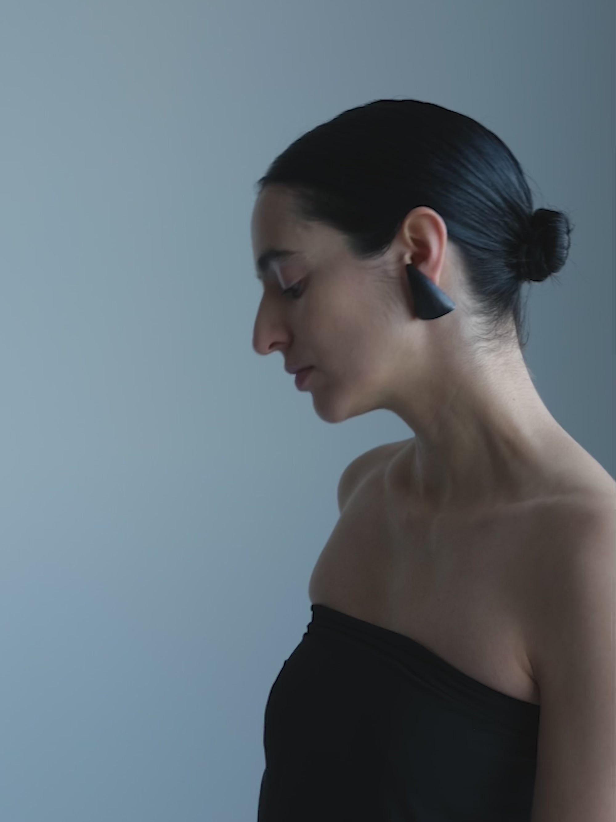 Woman wearing Black wooden triangular earrings on a white background