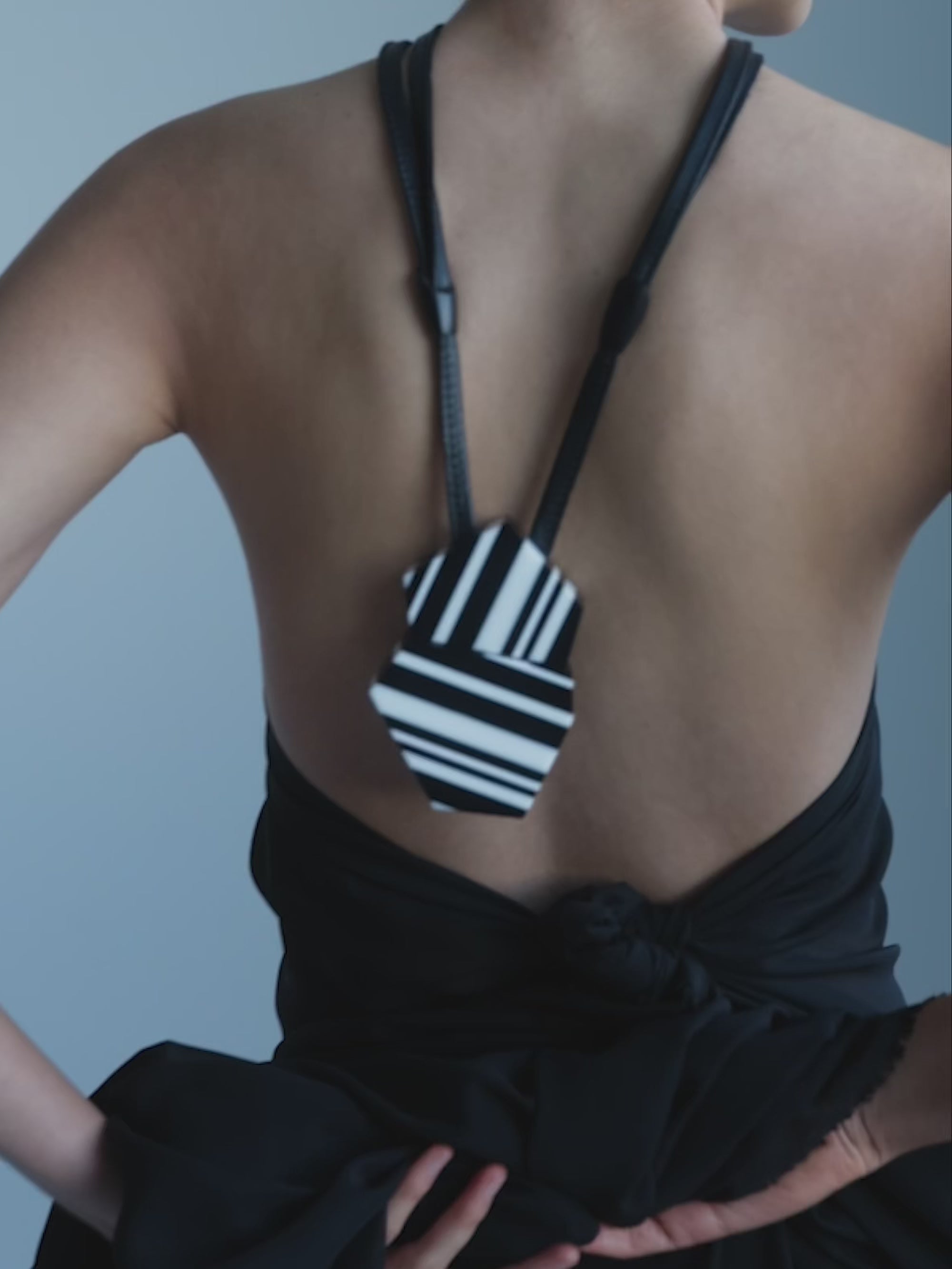 Woman wearing a black and white striped pendant with a black leather cord on a white background