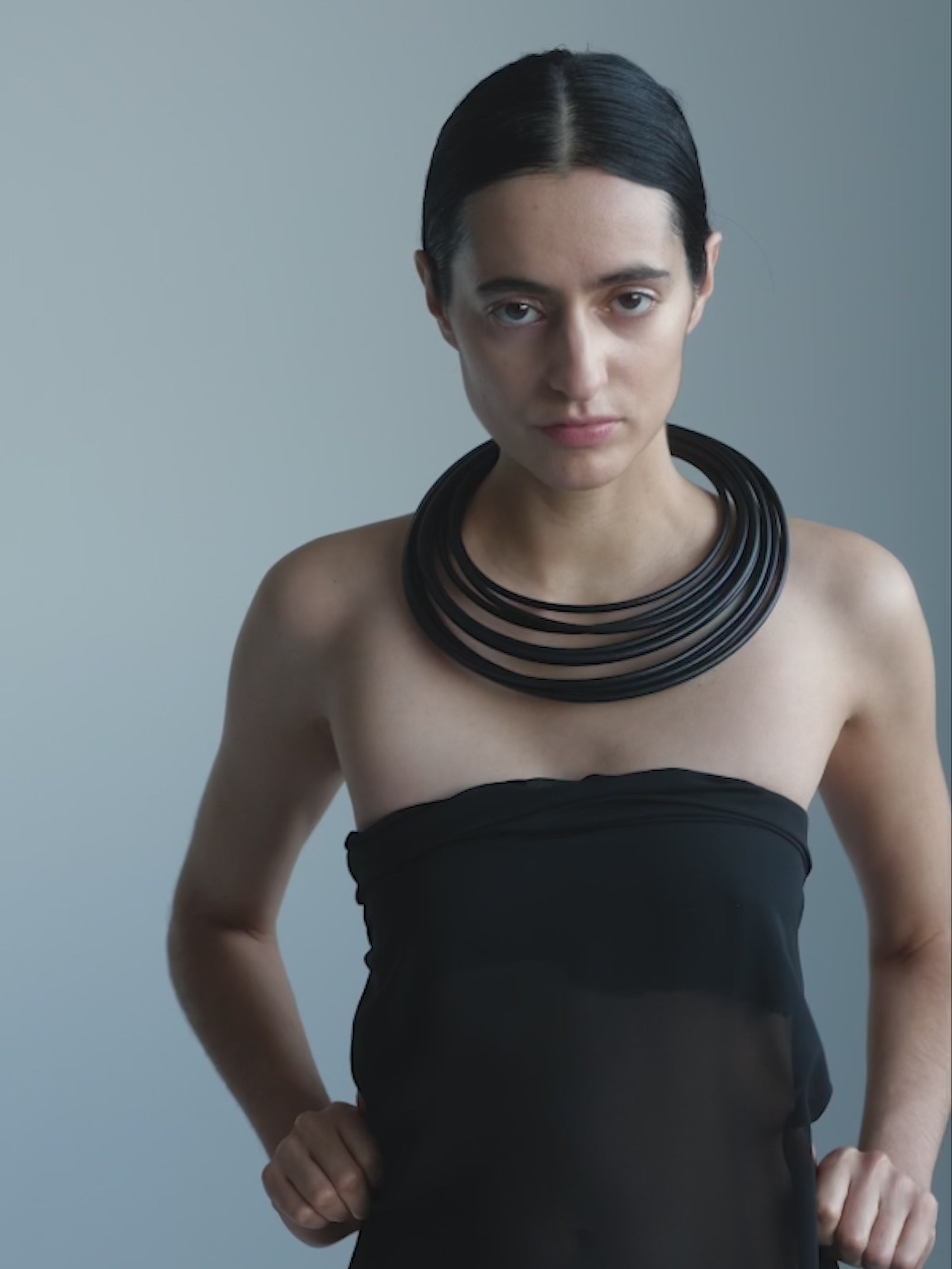 A woman wearing black clothes wearing A black leather and bog oak necklace on a white background
