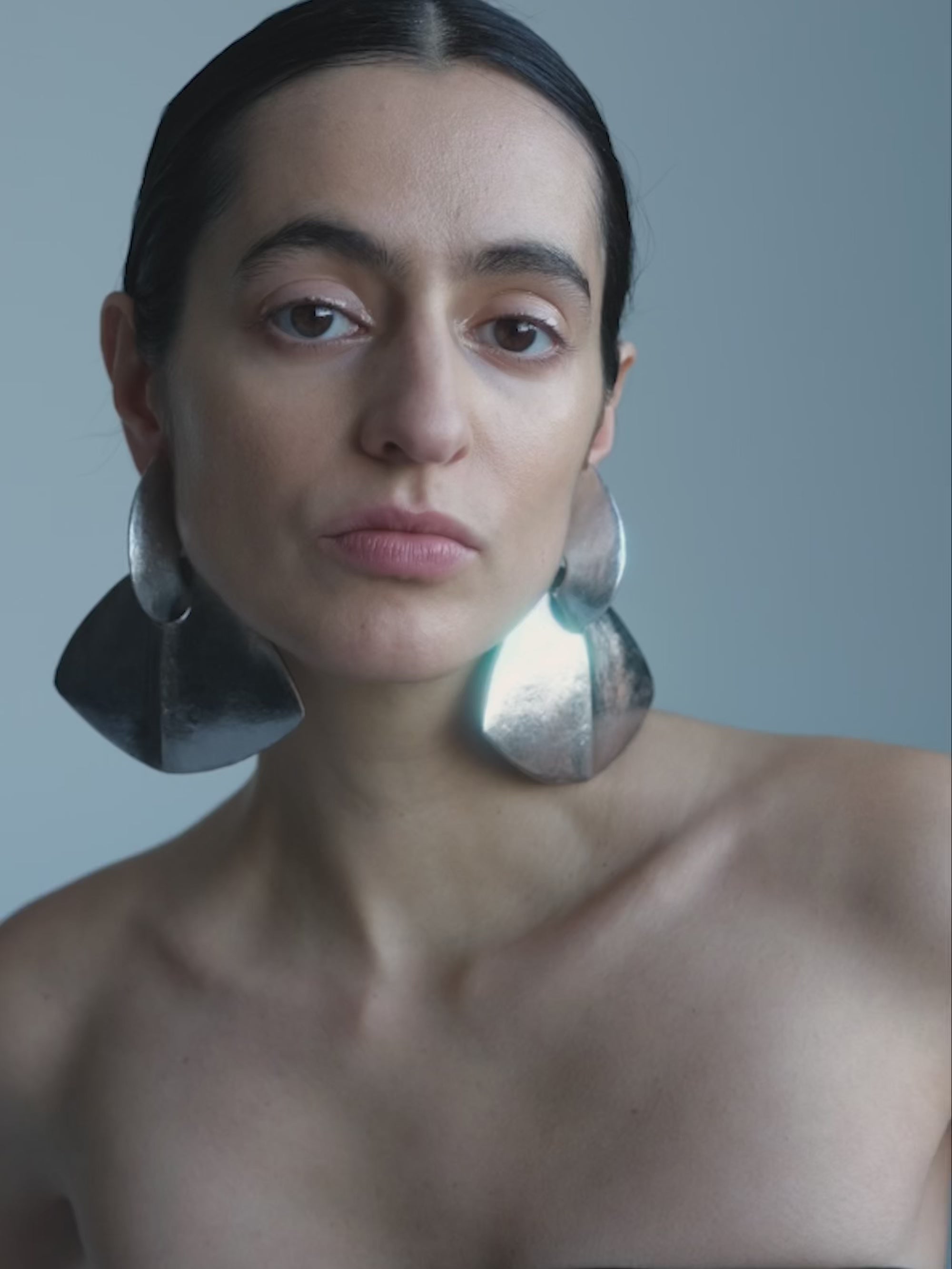 Woman wearing a Pair of silver triangle earrings on a white background
