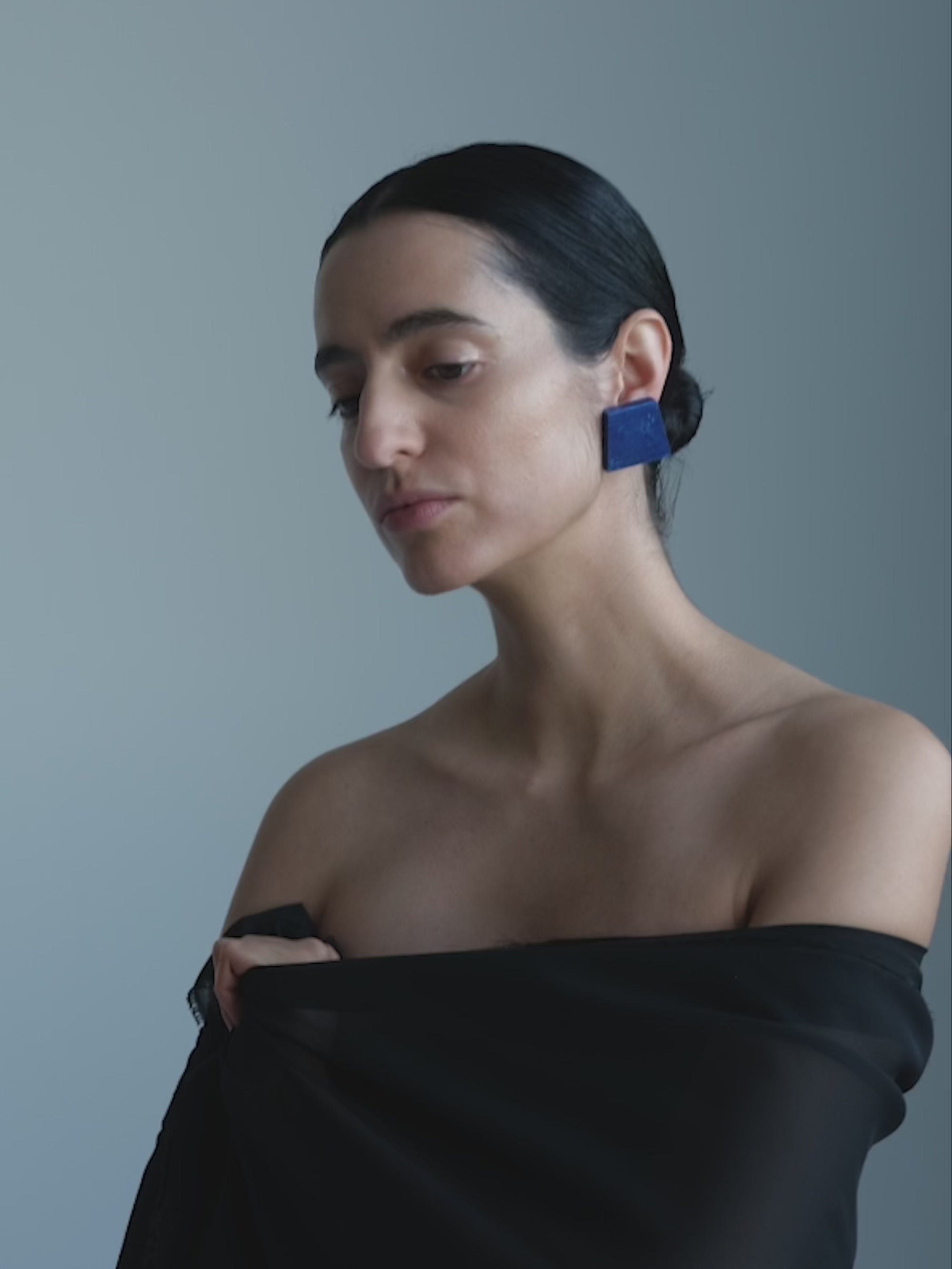 Woman wearing A pair of blue square earrings on a white background