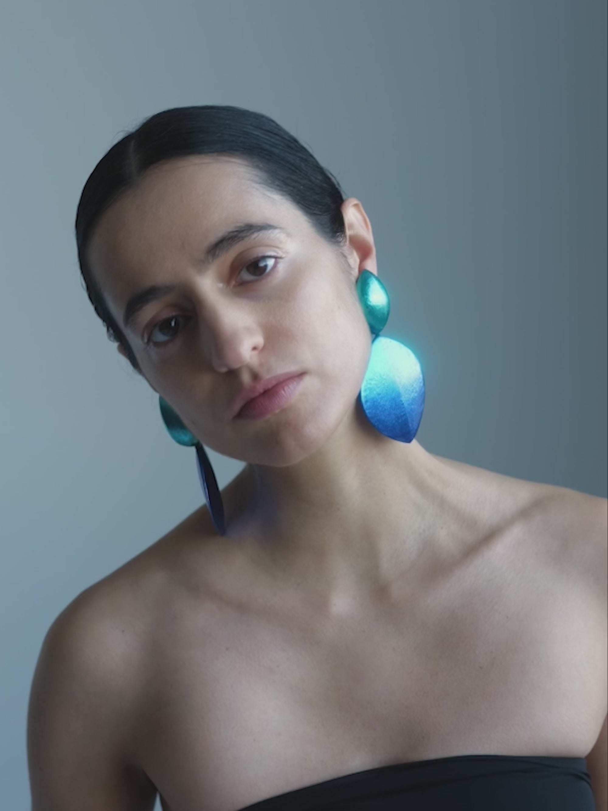 Woman wearing Blue drop-shaped earrings on a white background