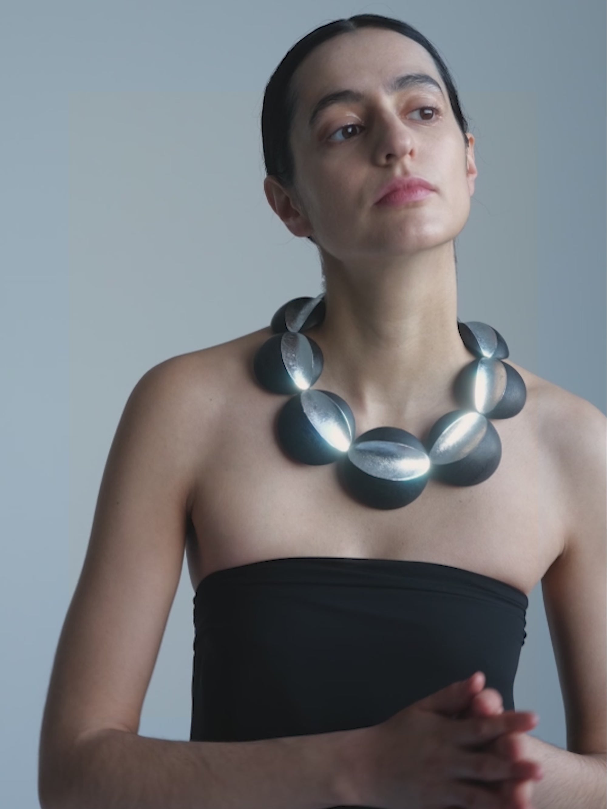 A  woman wearing Black and silver beaded necklace on a white background
