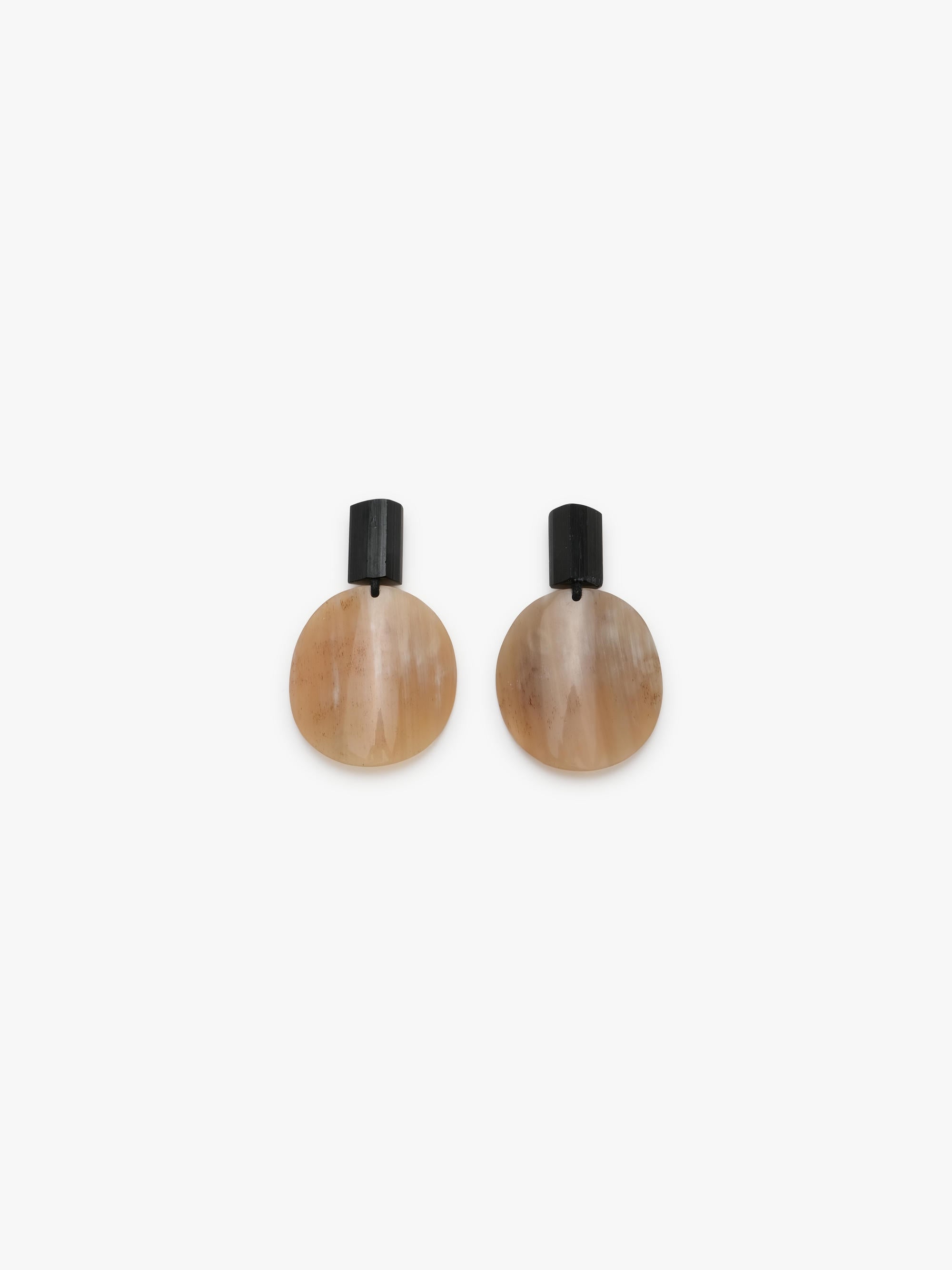 A pair of minimalist drop earrings featuring organic, teardrop-shaped beige and brown horn pendants with black stone posts, shown against a plain white background.