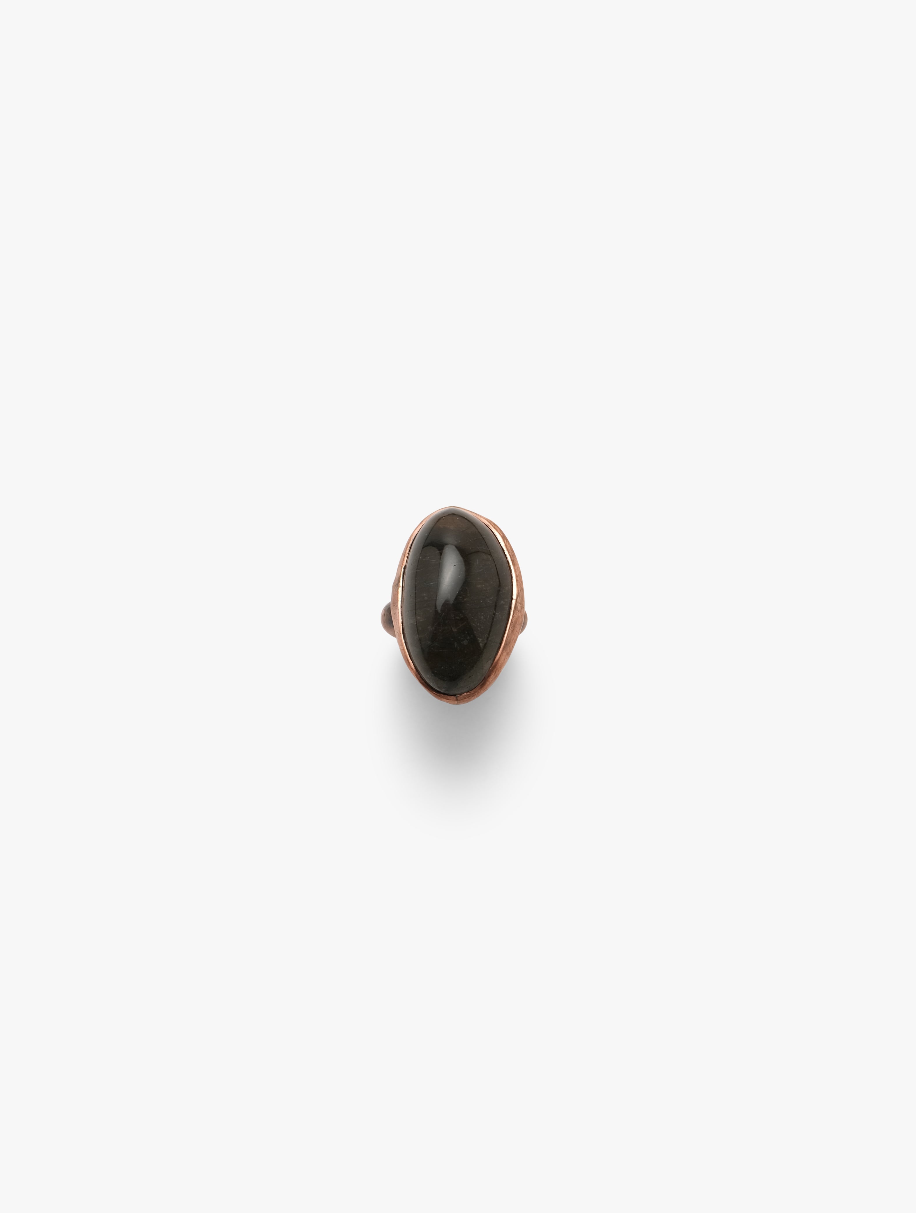 A copper-colored band ring with a black quartz crystal in the center, set on a plain background.