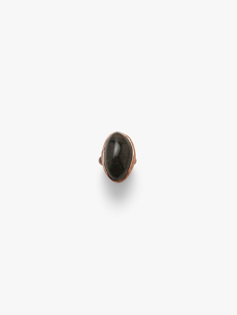 A copper-colored band ring with a black quartz crystal in the center, set on a plain background.