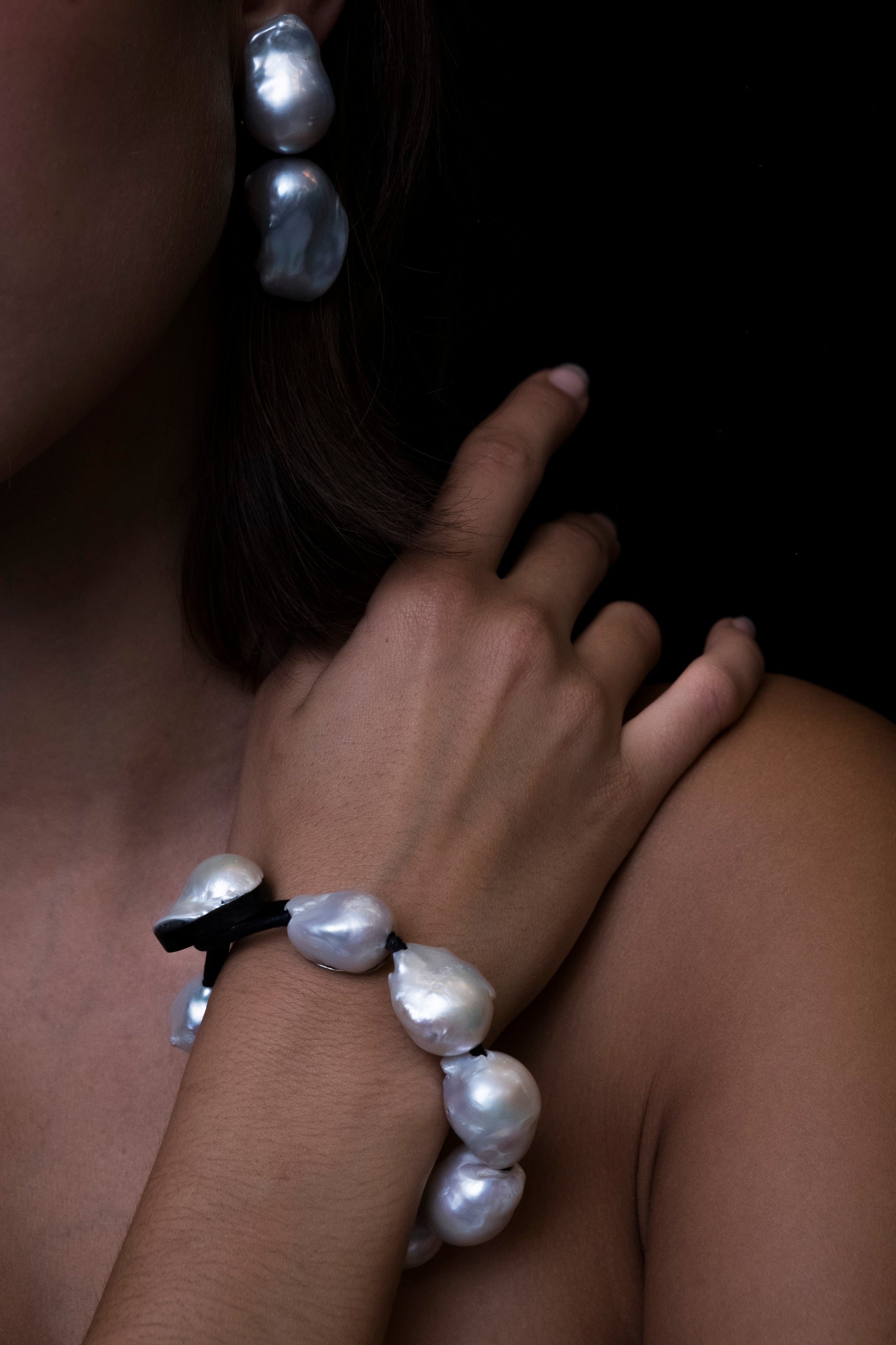 A bracelet made of baroque pearls with a leather strap, featuring a toggle clasp lock.